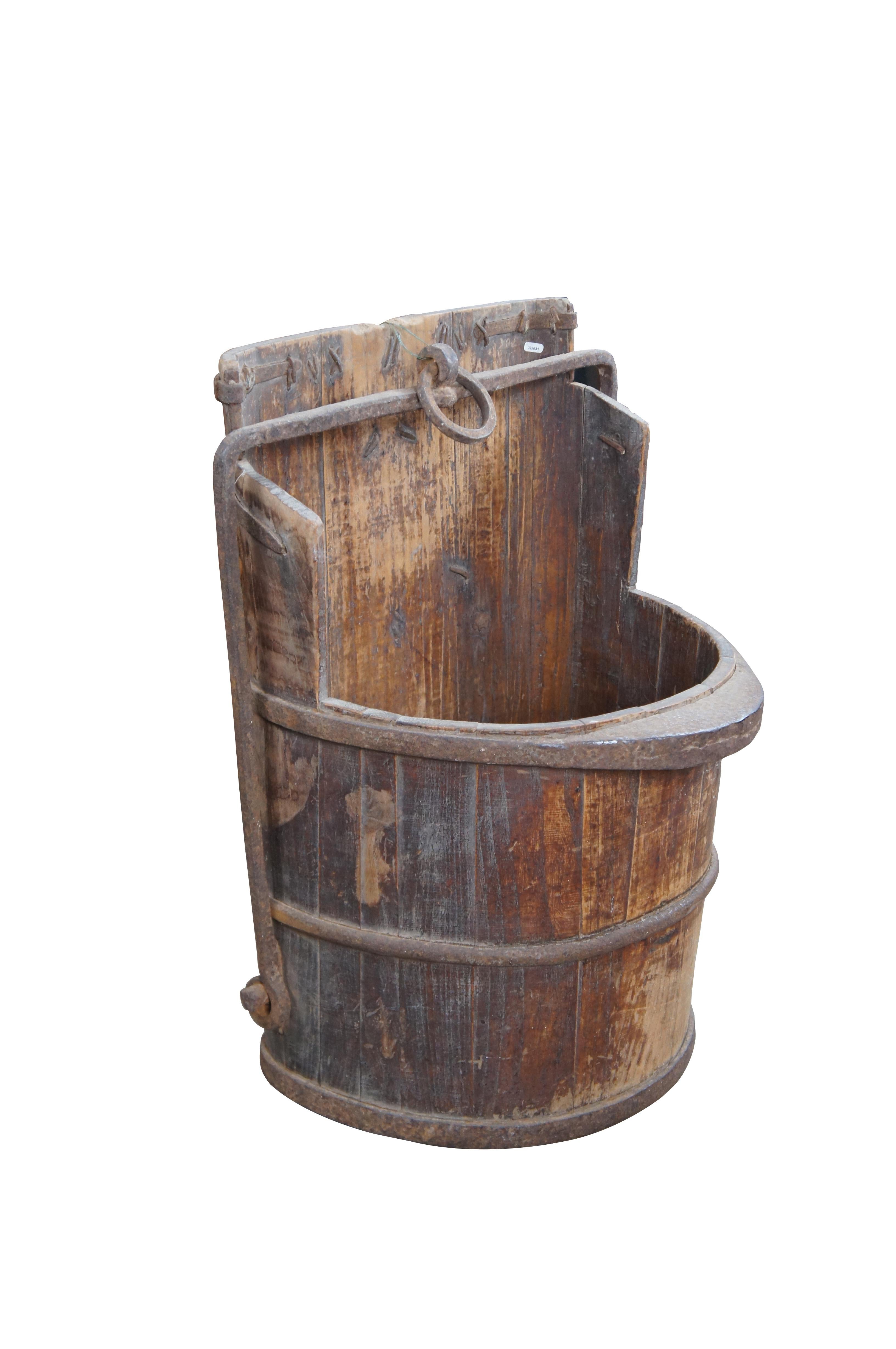 Primitive Chinese water bucket, circa 1890s-1910. Made elm and forged iron. Beautifully worn from years of use. A great decorative piece that could also be re-purposed as a planter, garbage can, cane or umbrella stand.

Dimensions:
26.5
