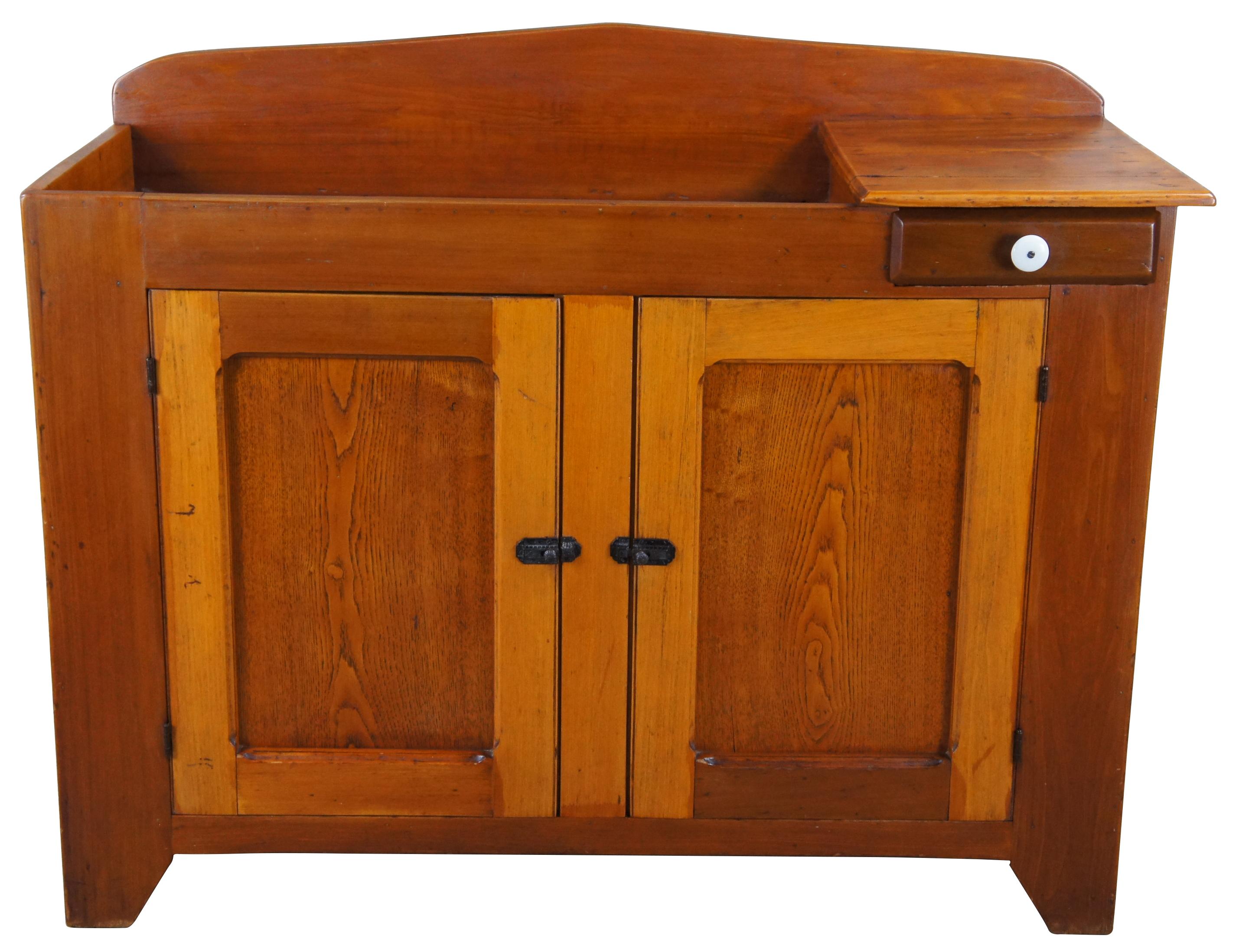 Primitive antique farmhouse dry sink. Made from oak and pine. Features a large basin with a small work surface over a drawer and lower cabinet with shelf for storage. Lower aprons along the side have a serpentine cut apron Latches along the lower