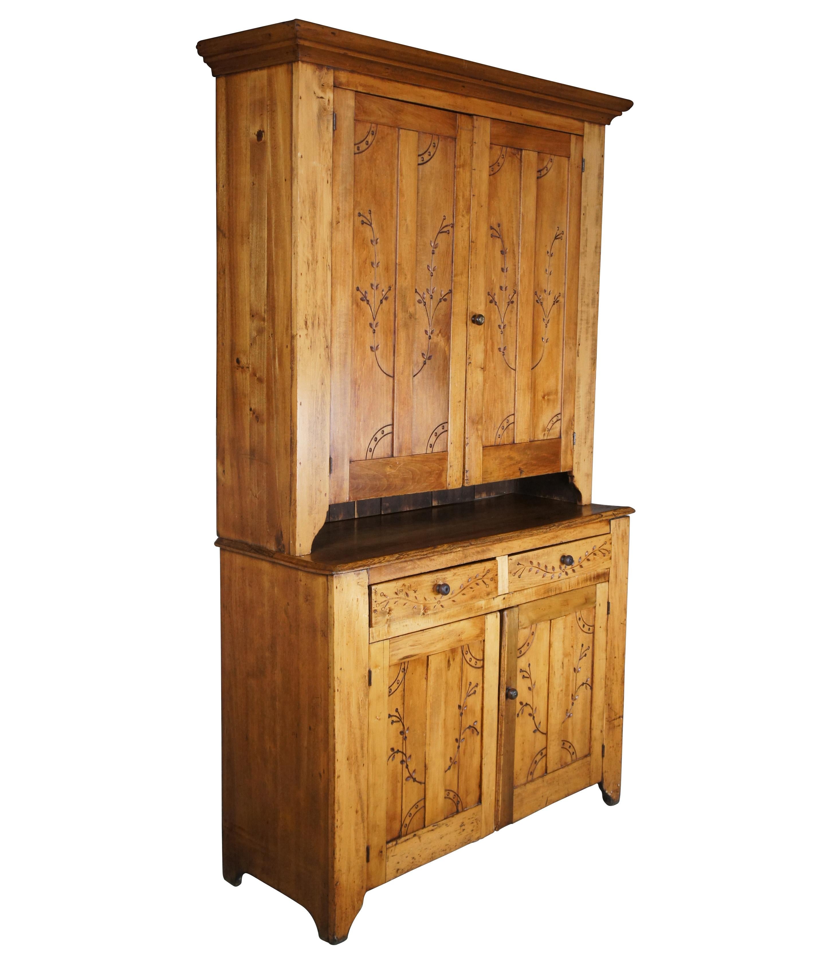 Early 20th century American blind door step back cupboard. In the manner of Pennsylvania Dutch. Made from oak with foliate carved doors and drawers. Opens to three shelves with plate grooves on the hutch and one large shelf on the base for accessory