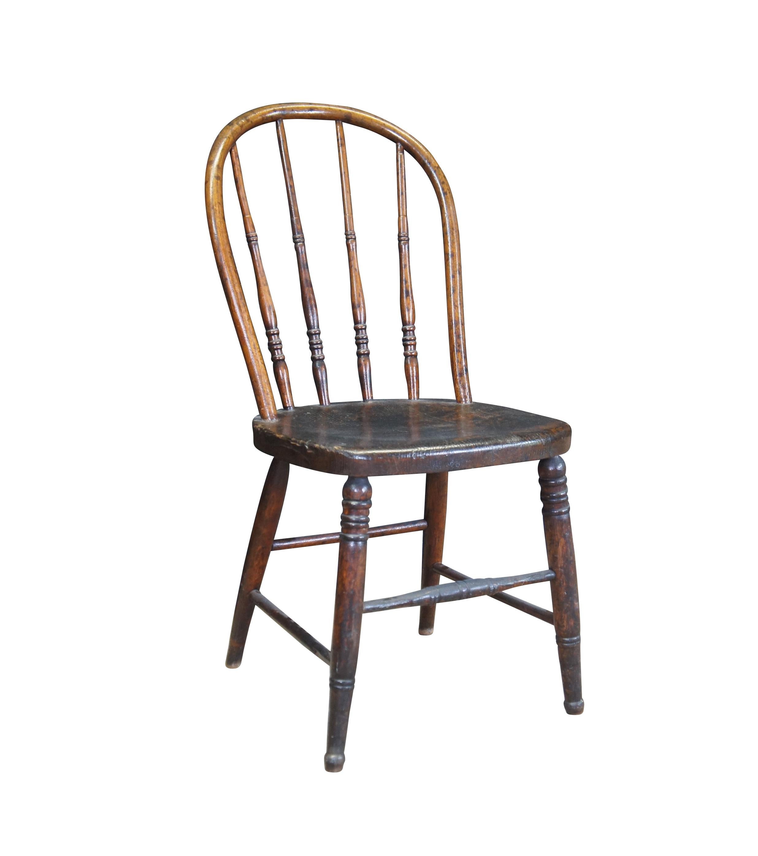 Quaint antique windsor bowback chair. Made from oak with a warm brown finish. Features a turned spindle back over plank seat and turned legs connected by stretchers.
