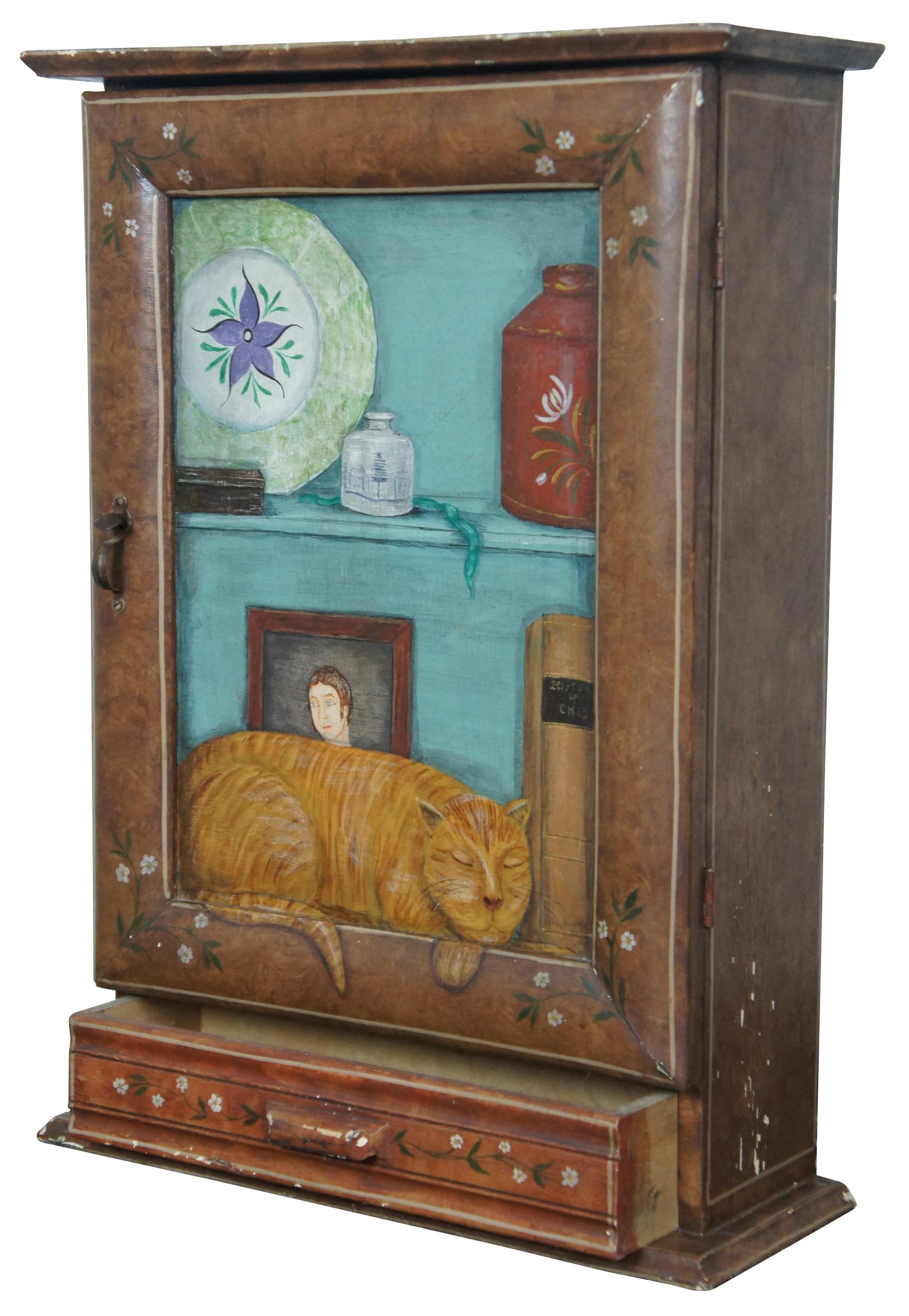 Antique wooden wall hanging medicine cabinet painted with flower accents and a central panel painted to look like the cabinet is full of objects and a sleeping cat. Interior is painted blue with a pineapple on the back of the door.
  