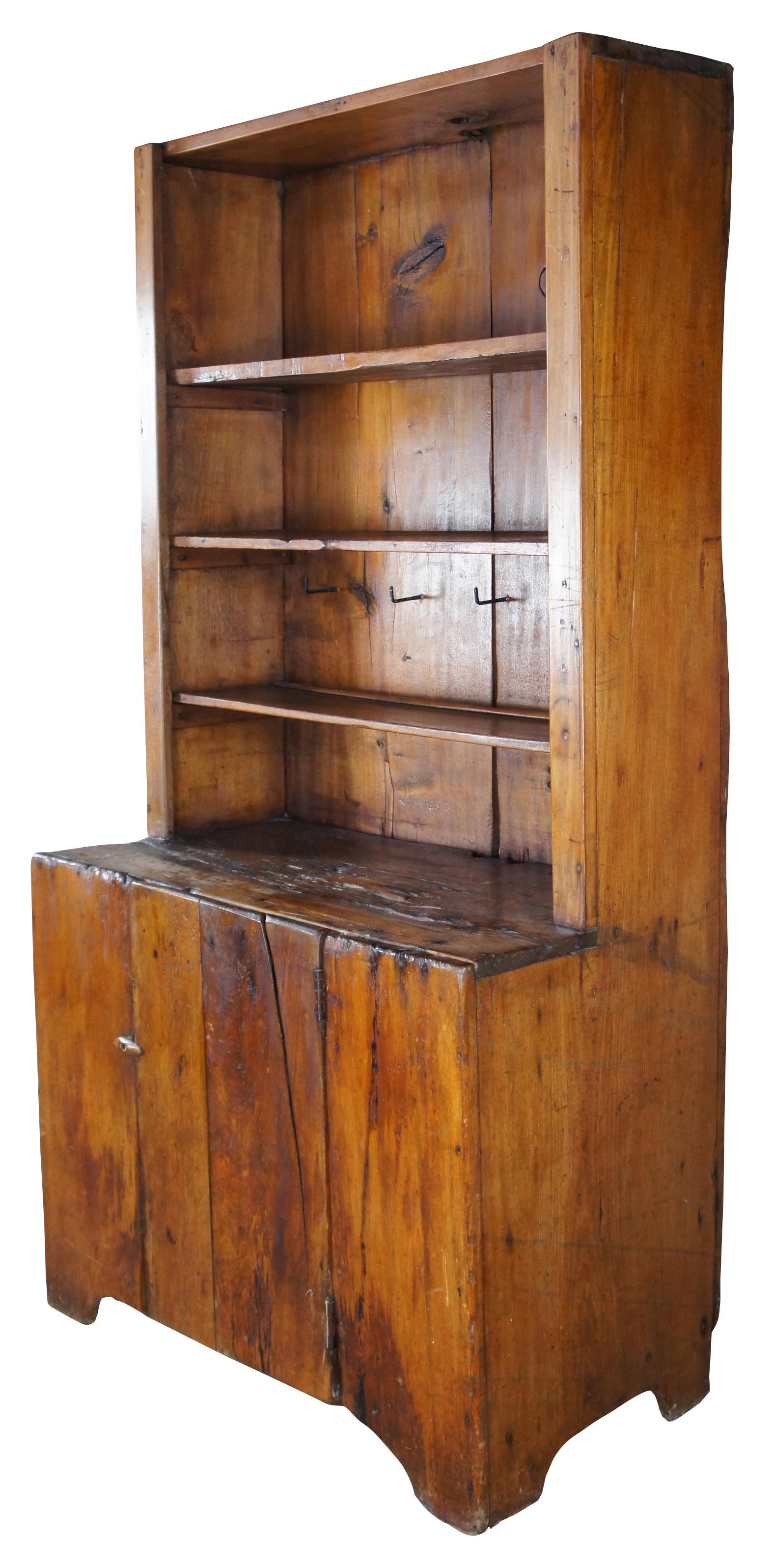 Late 18th century American pine pewter cupboard. Features a stepback from with removable shelves and iron hardware for hanging cups. Lower section opens via latch to additional storage area with shelf. This beautiful piece shows incredible signs of