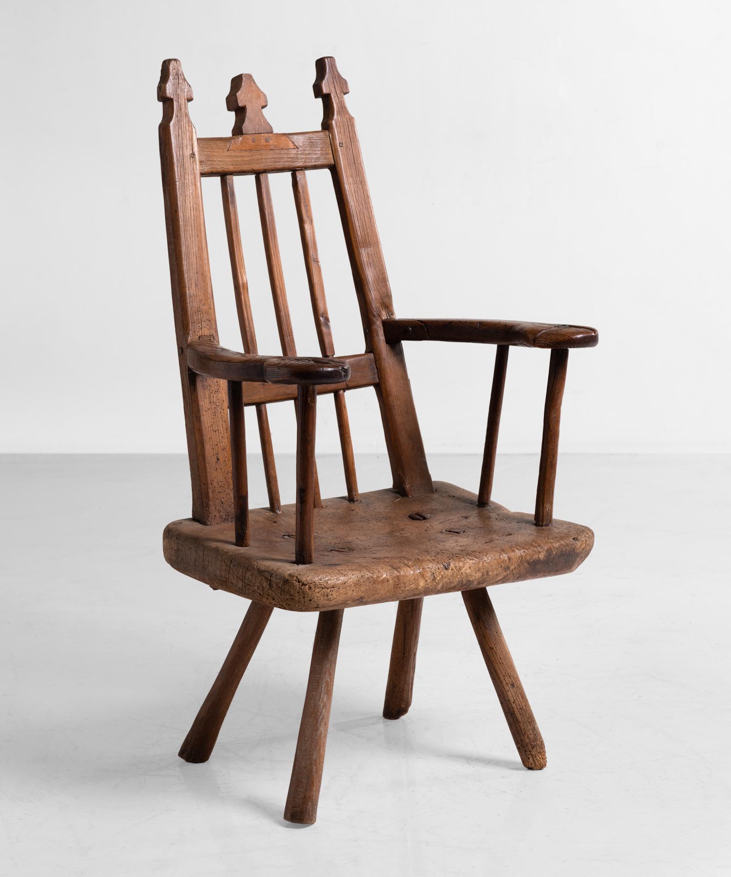 Primitive wooden armchair, England, circa 1820.

Unusual high back chair in ash and oak with shaped finials and six straight spindles on a slab seat.
