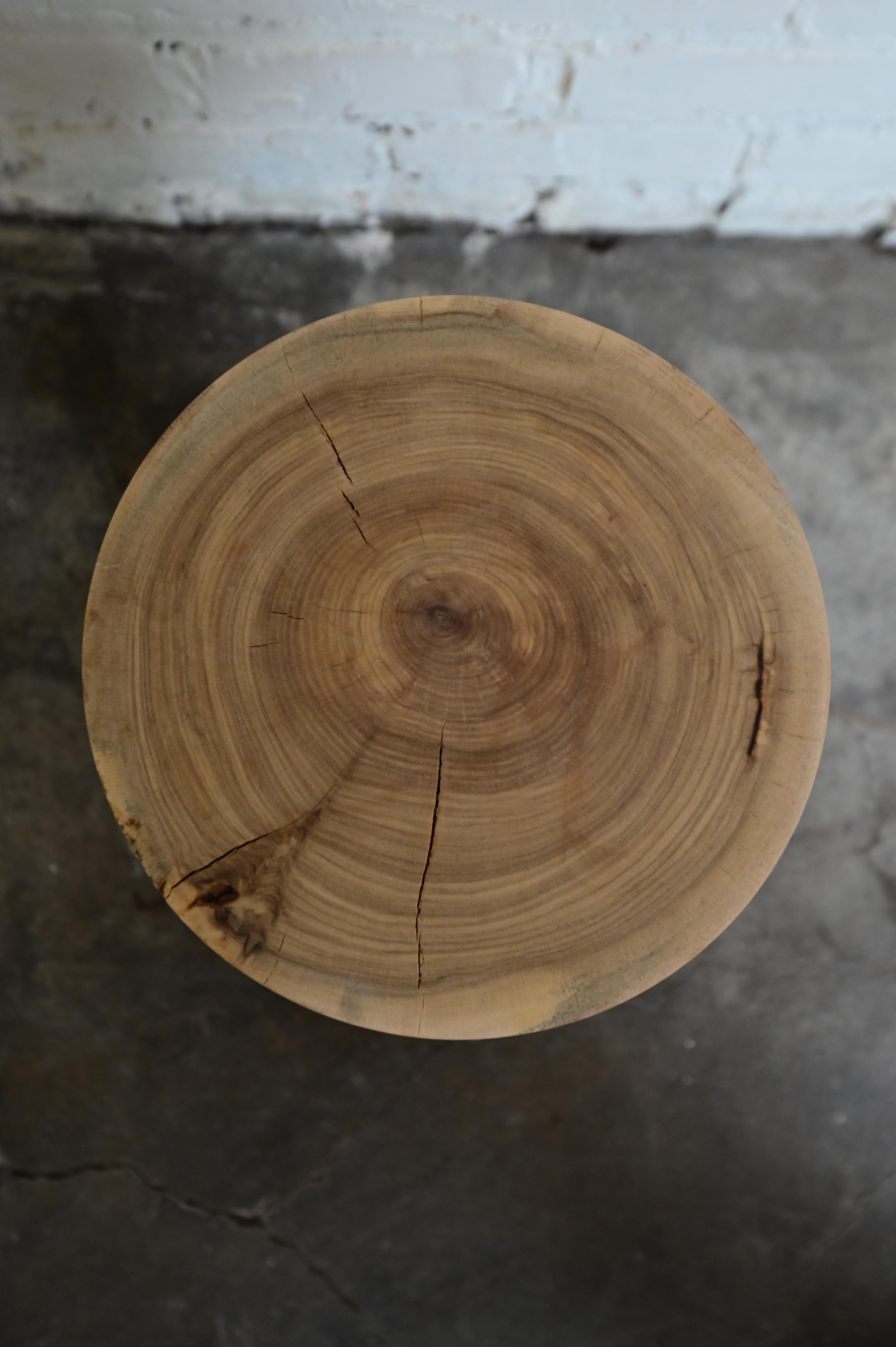 Table d'appoint en bois unique, sculptée à la main. Sculptée en bois massif, elle mesure 16 pouces de haut et 9 pouces de diamètre en haut et en bas. La pièce est fabriquée à partir de matériaux naturels, de sorte que de petites fissures et des