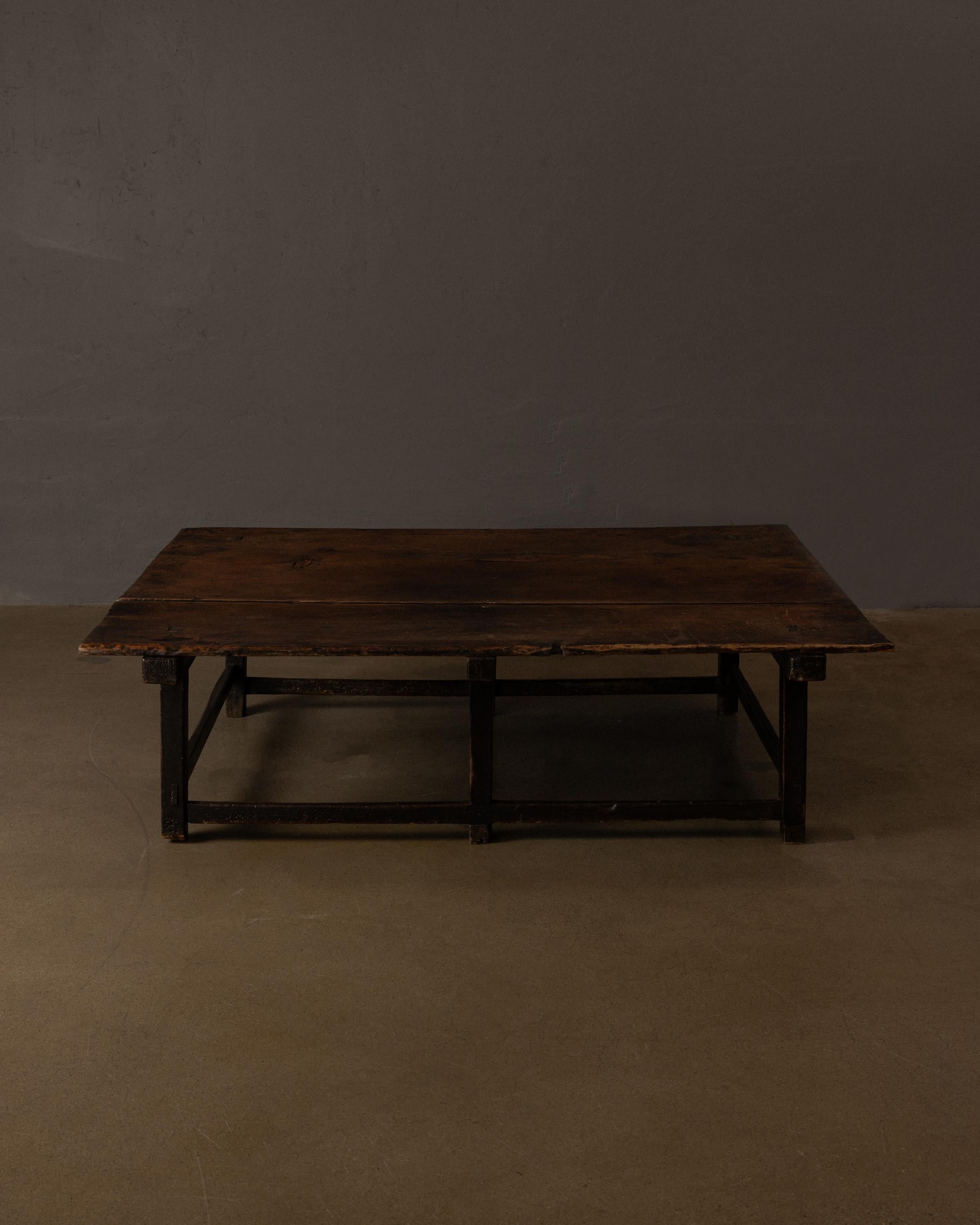 Mesa de centro compuesta de tablones de madera tallados a mano con nudos visibles, grietas y llaves de mariposa