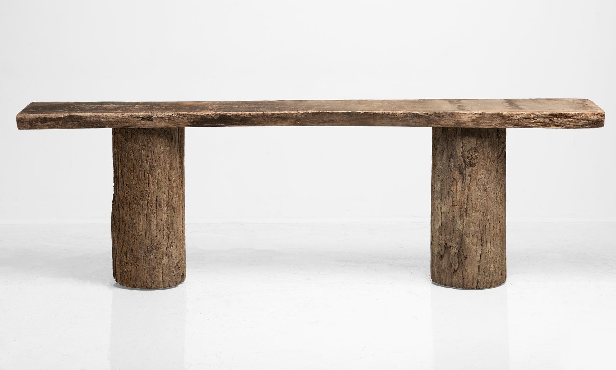 Single slab of wood resting on top of two tree trunks.
 