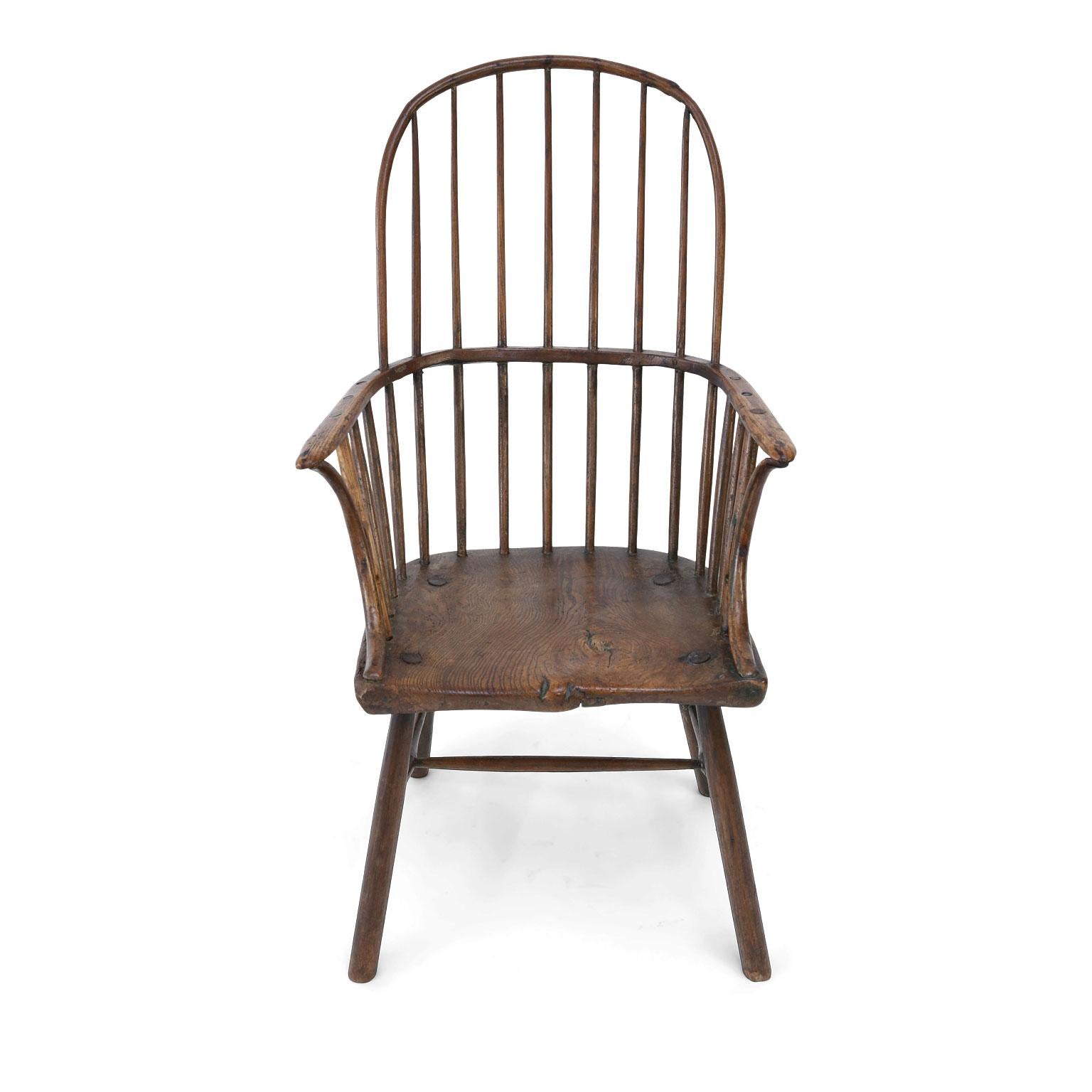 Primitive Cornish Windsor chair (circa 1750-1770) with a thick shaped seat fashioned from a slab of elm, supported by straightforward drawn legs and H-stretcher. Features a simple stick-and-hoop back, with a charming old repair and interesting