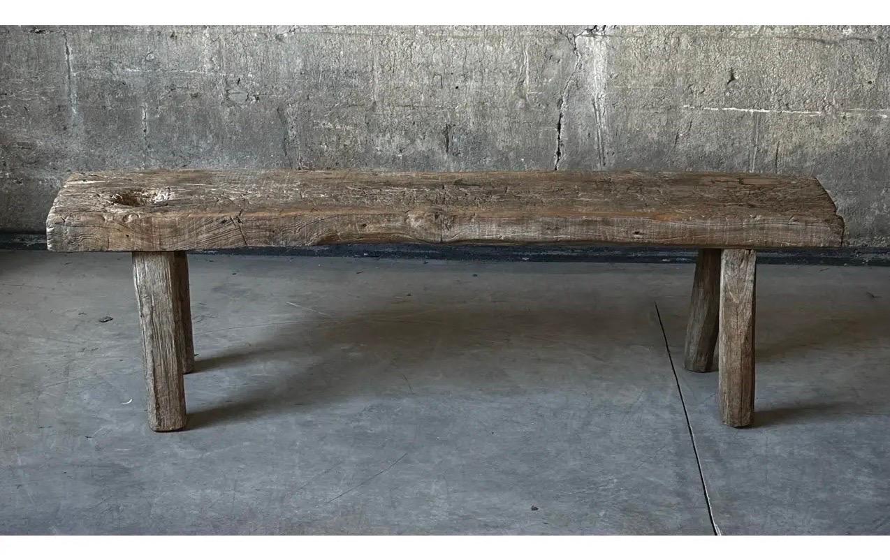 Ce banc en planches de style primitif a TELLEMENT de caractère ! Originaire du Portugal, il est fabriqué en bois d'orme massif et richement grainé. Il manque un nœud à l'une des extrémités (voir illustration). Le bois naturel présente une belle