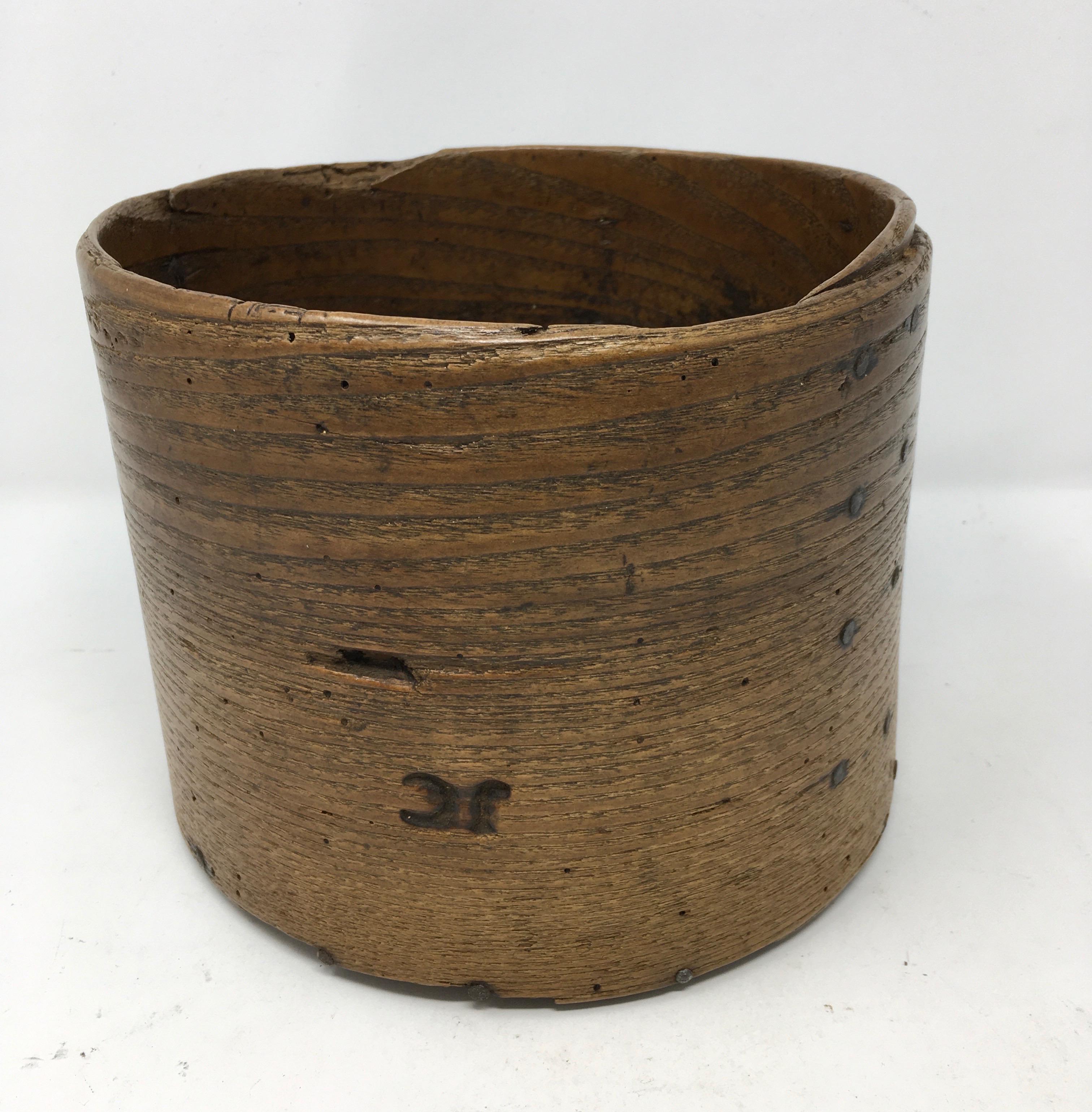 Found in England, this 19th century primitive grain measure is made with a single piece of wood bent into a barrel shape secured by tiny rivets around a round bottom piece of wood. The piece, stamped JC has fabulous aged wood patina and would be