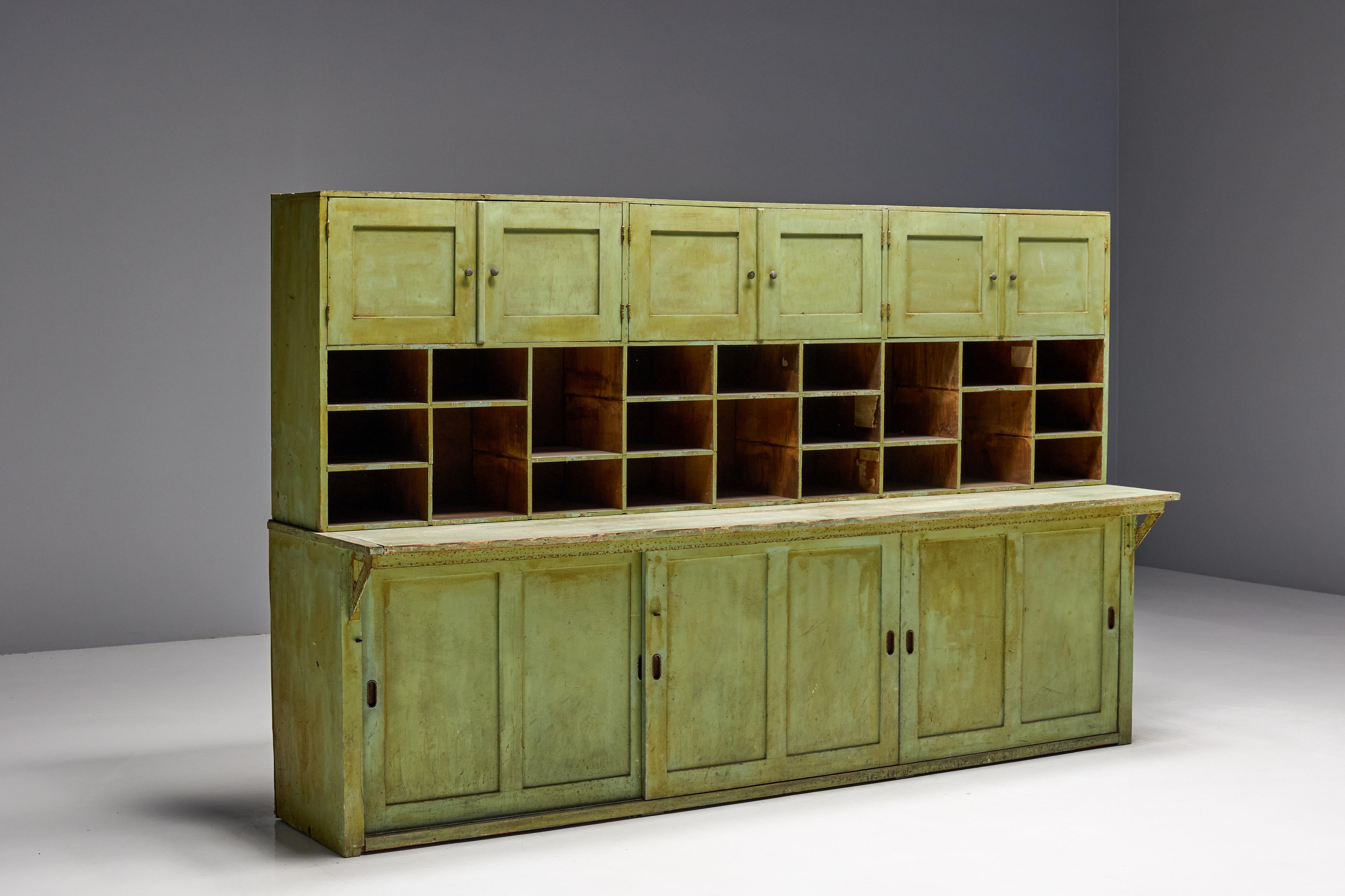 Apothekerschrank aus dem 19. Jahrhundert mit originaler grüner Patina, die bis zur Perfektion abgenutzt ist. Die vielen Fächer und geräumigen Unterschränke des Schranks bieten praktischen Stauraum, der sich sowohl für moderne als auch für