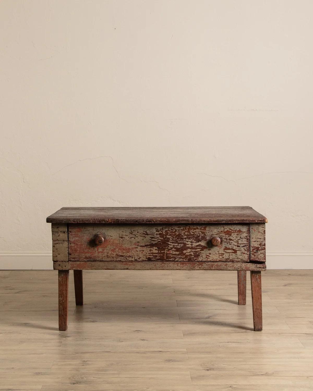 Cette table basse du 19e siècle, provenant d'une table ancienne plus grande et réduite à sa taille, présente une finition de peinture verte magnifiquement vieillie qui révèle des couches d'histoire et d'utilisation. La patine usée ajoute de la