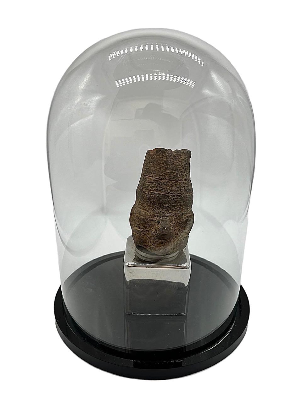 Primitive Kopffigur aus der präkolumbianischen Zeit aus Stein und auf einem speziell angefertigten Chromsockel stehend. Das Stück ist in einer Glaskuppel mit schwarzem Lucite-Sockel untergebracht.

8in x 6in (Glaskuppel).