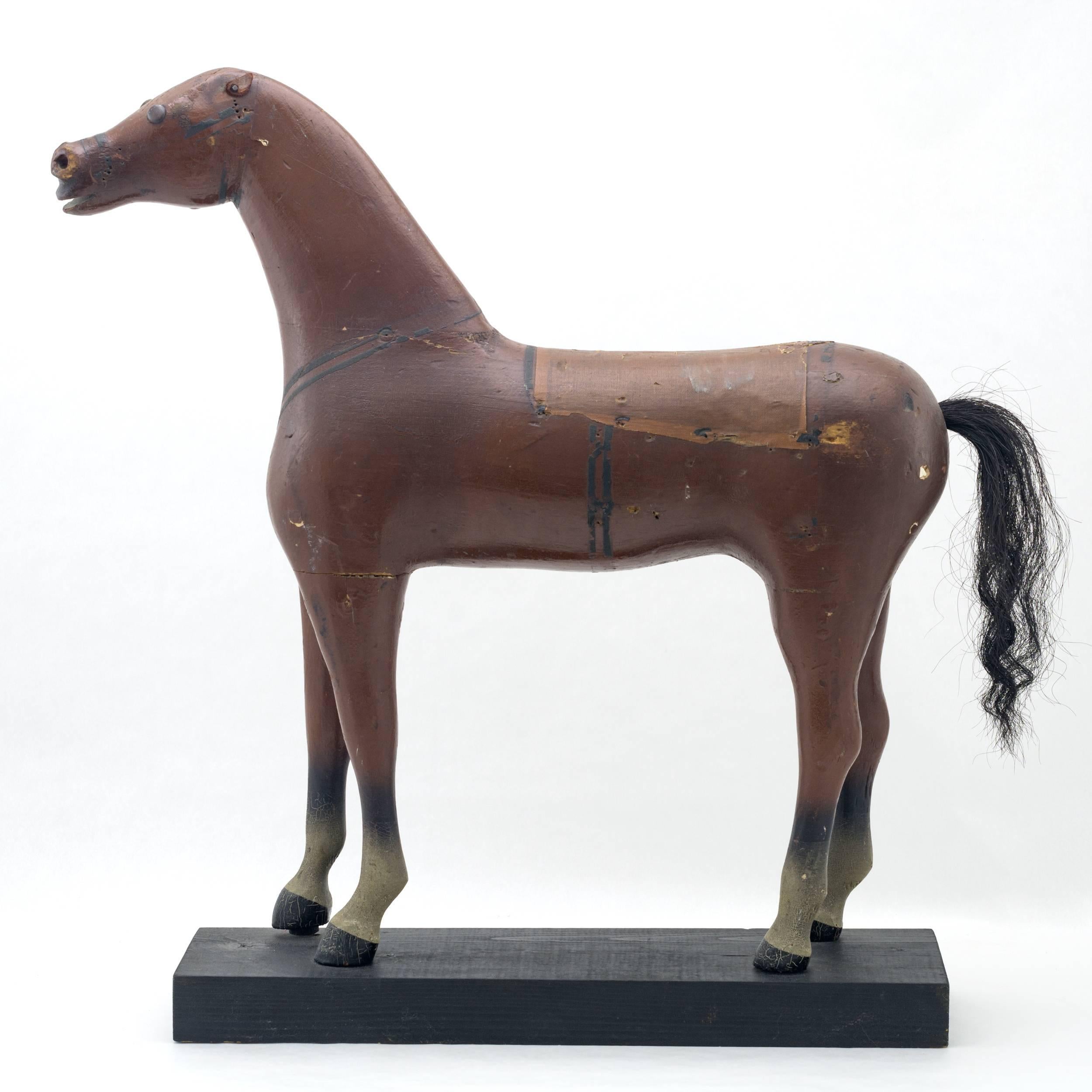 Cheval debout en bois sculpté et peint au gesso.
avec selle en tissu peint et queue en crin de cheval
Monté sur une plate-forme peinte en noir fabriquée ultérieurement.
 
      
      