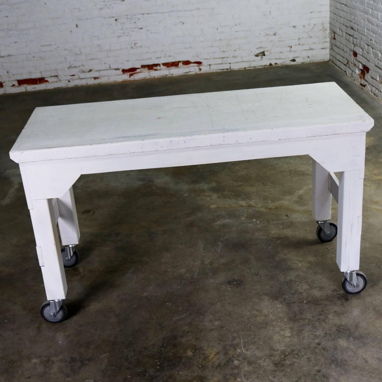 Wonderful primitive white painted rolling work table or kitchen island in a farmhouse or industrial style. This piece is in awesome condition with a beautiful distressed finish and patina, circa 20th century.

We found this primitive distressed