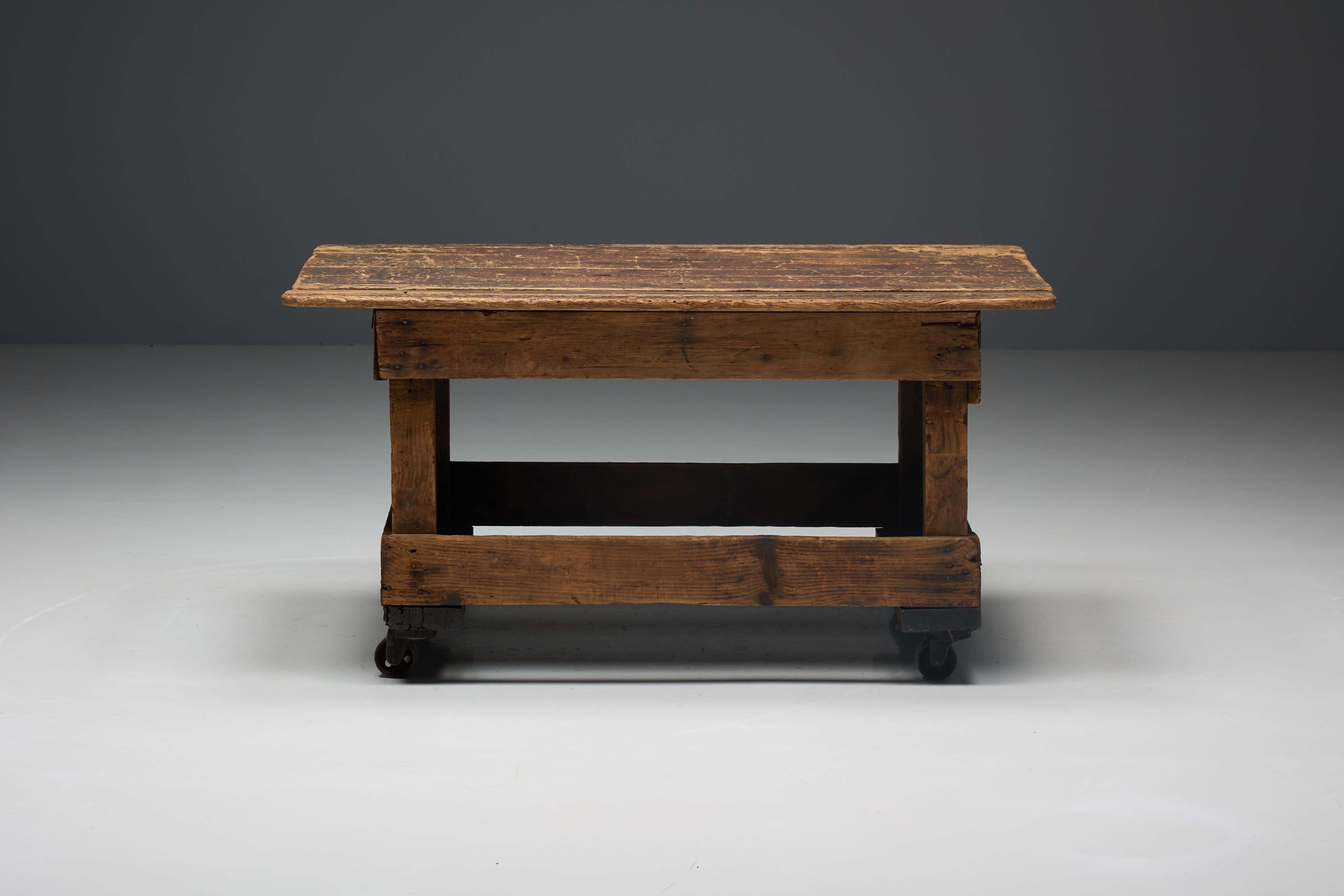 Rustikaler französischer Industrietisch, der den rauen Charme von altem Holz mit funktionaler Mobilität dank seiner robusten Räder verbindet. Ideal als Couchtisch oder als funktionelle Werkbank, verleiht dieses Stück jedem Raum Charakter und