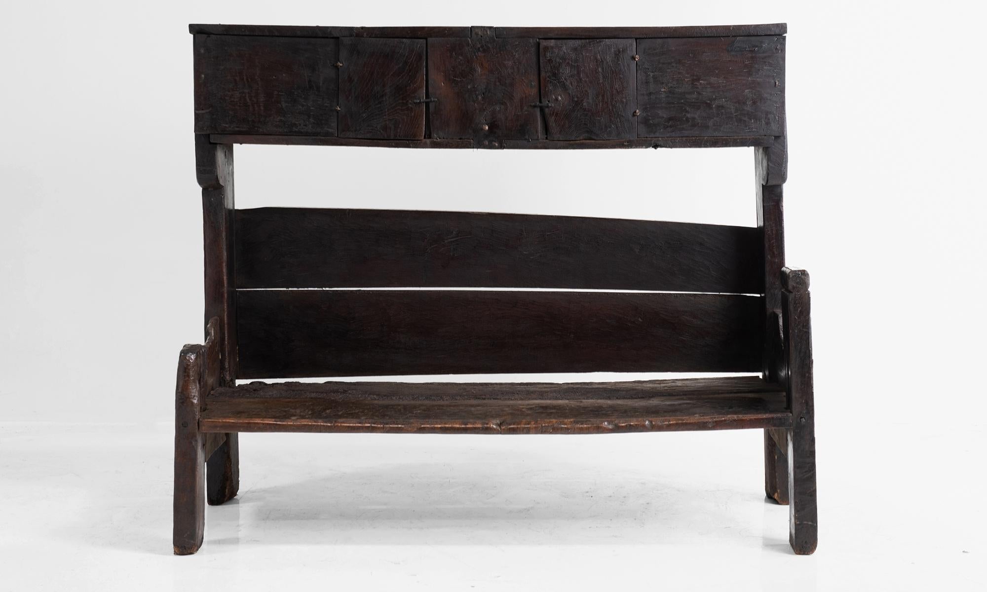 Incredibly unique bench recovered from a 15th century church in the Pyrenees Mountains. Constructed from slabs of heavy oak with storage above the bench.