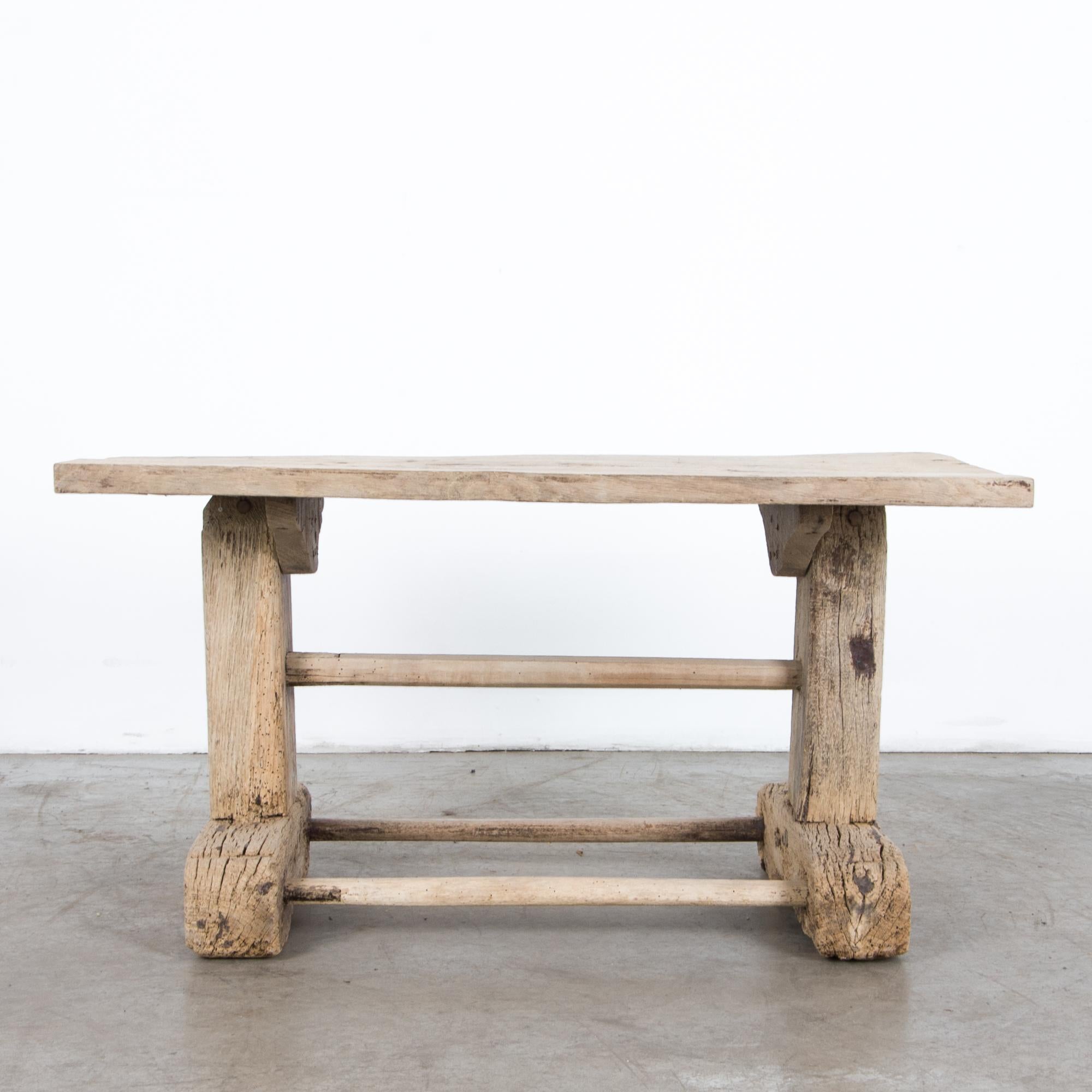 A rustic French table constructed from thick oak beams. A well grounded base with architectural proportions supports a thick top, with rustic worn patina. At 19.5” high, this is a great accent in a space craving character.