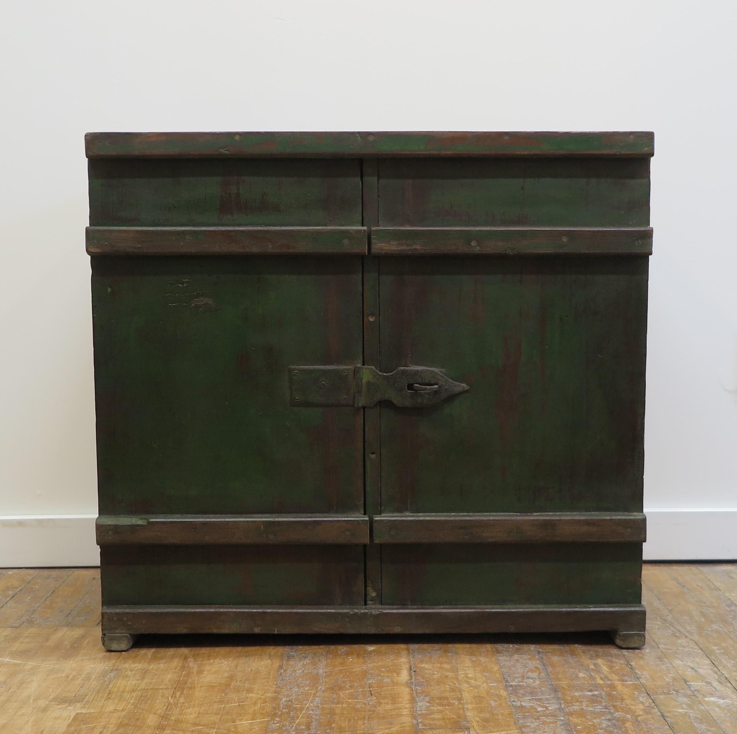 Primitive Painted Cabinet. Primitive Side Cabinet with sliding doors. Great interesting Primitive side storage cabinet with nice patina of green paint that has oxidized nicely. Hand forged iron cross over hardware centered allows you to add a lock.