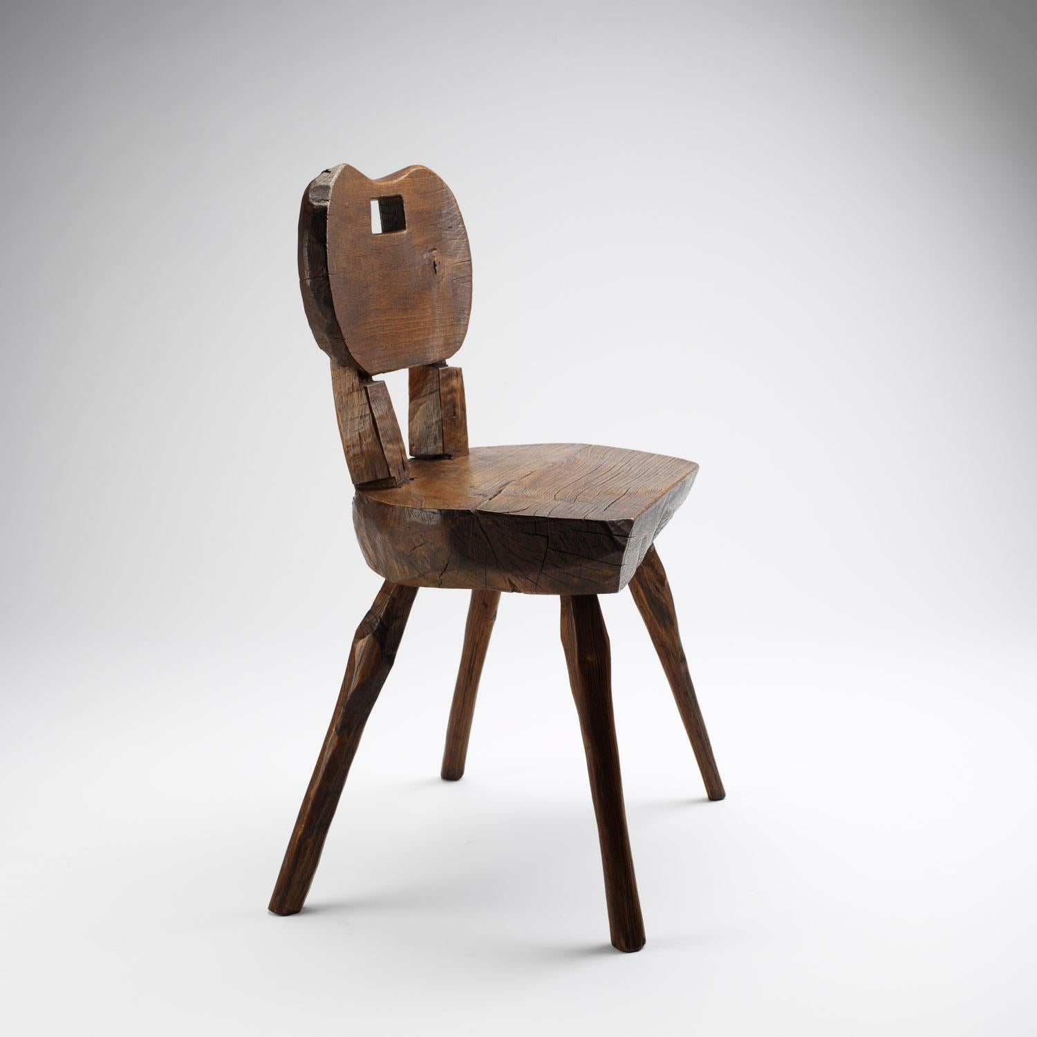 A primitive handmade Alpine chair in solid ash. Strong, naive construction with a rounded back and handle, France, early 1900s.