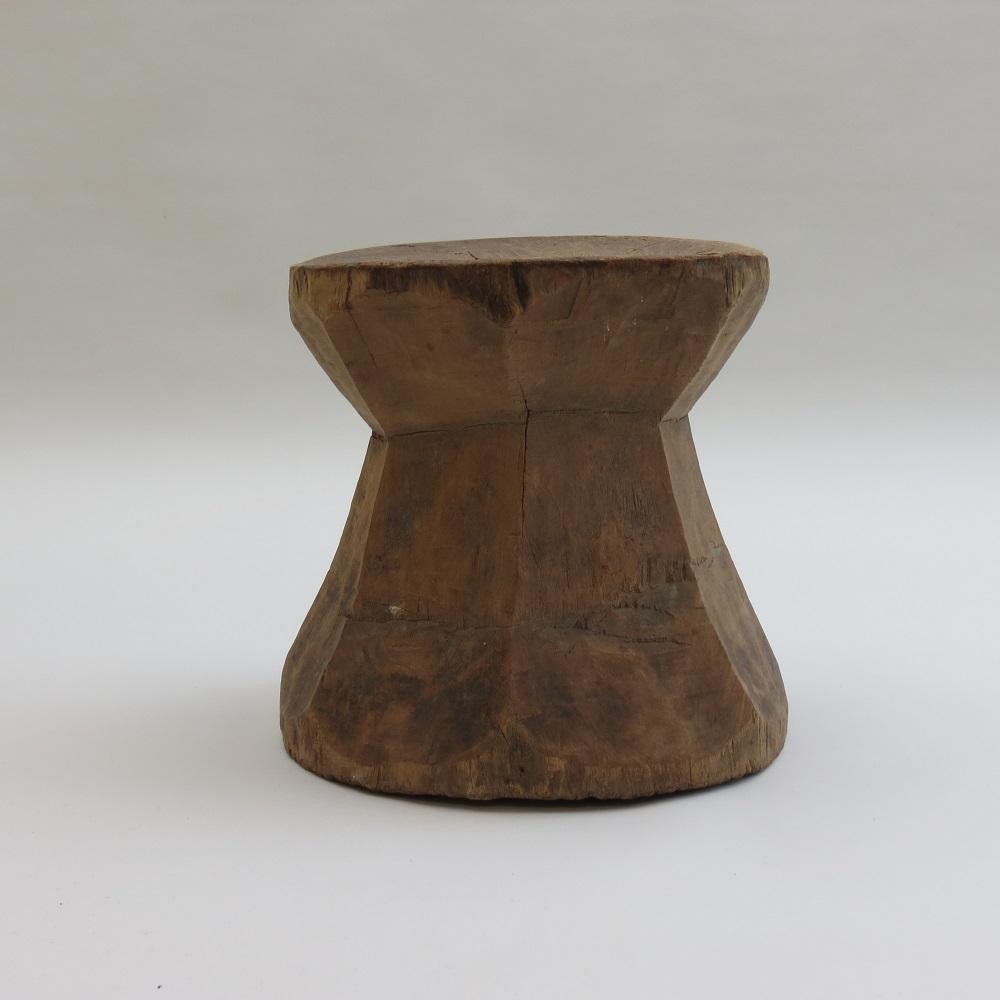 A wonderful primitive rustic wooden mortar stool or table. 
Made from hardwood, this piece has been hand crafted using and adz (axe) tool and retains adz marks all over from the process of hand cutting away the wood to produce its form. 
The piece