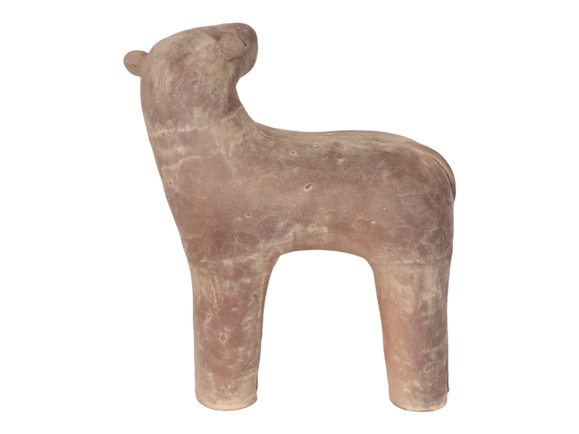 A primitive sheep sculpture made of clay. Simply shaped with marks for the eyes, nostrils and mouth, as well as on the feet to indicate hooves. One ear has been reattached, the repair is secure, and visible in the pictures.