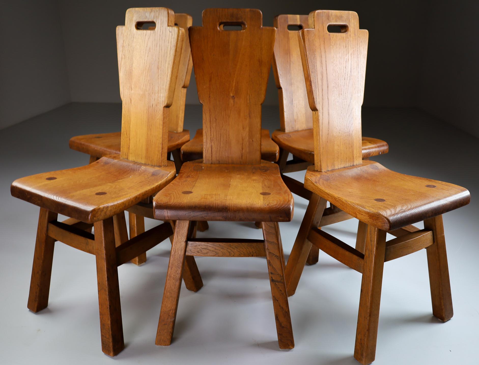Set/6 solid oak dinning chairs, France 1950s. These chairs are made of oak and crafted by hand. The craftsmanship is still visible, they are made of solid oak wood and constructed with visible joints. Very nice original patina.