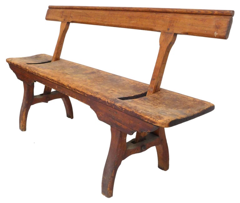 An outstanding, Primitive, turn-of-the-century wood bench. Incredible details and handmade craftsmanship with a wonderfully worn surface from age. A fantastic and highly-unusual hinged backrest, allowing one to sit on either side. An exceptional