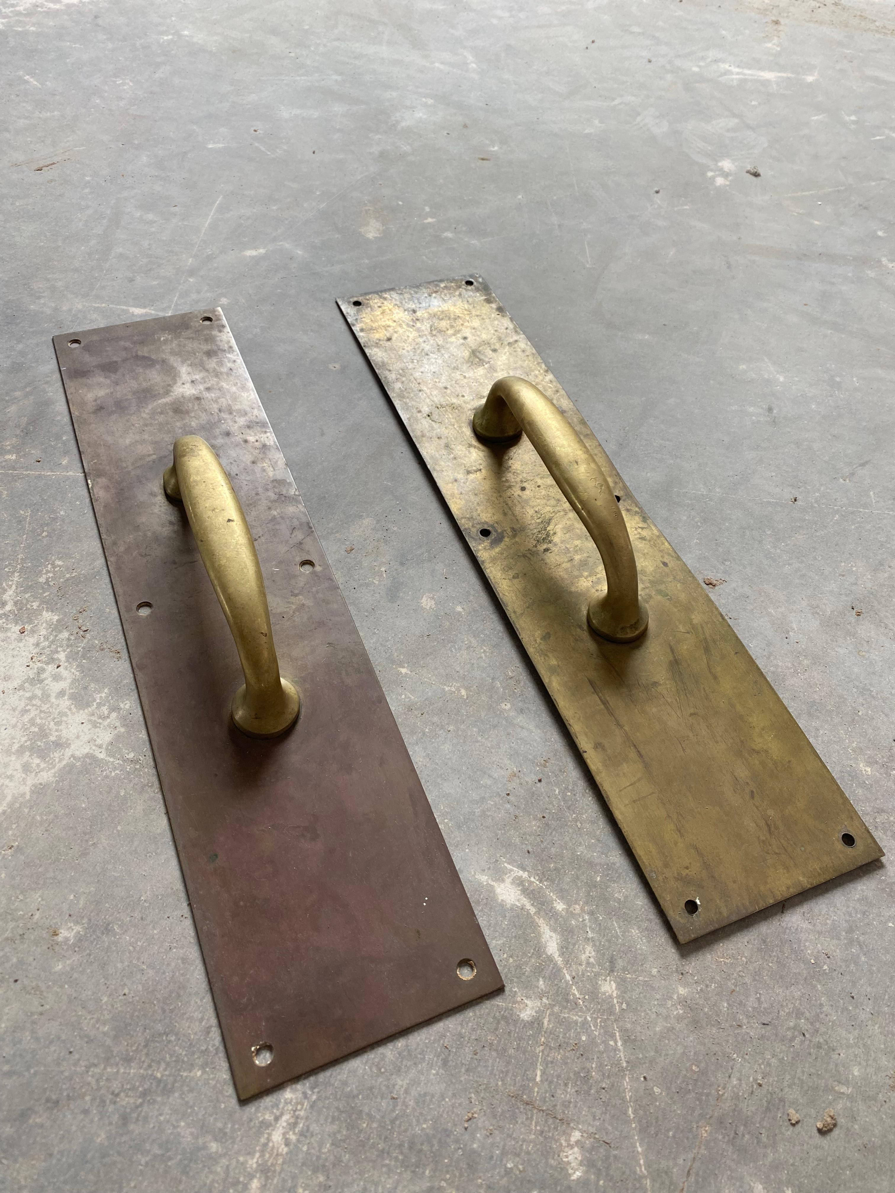 Primitive unlacquered brass cast brass door pulls attached to long, slim backplates. These have a patinated finish that has developed beautifully and naturally over the past 60-70 years. They date to the 1950s and were sourced in a mountain town in