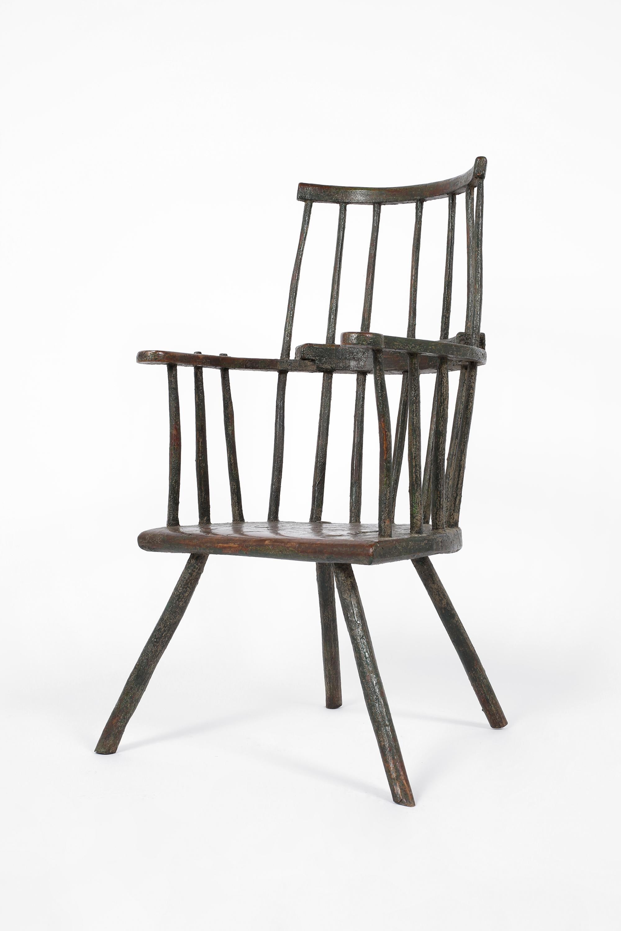 A sculptural primitive stick back chair of smaller scale, likely Welsh or Irish, heavily patinated with layers of distressed paint.