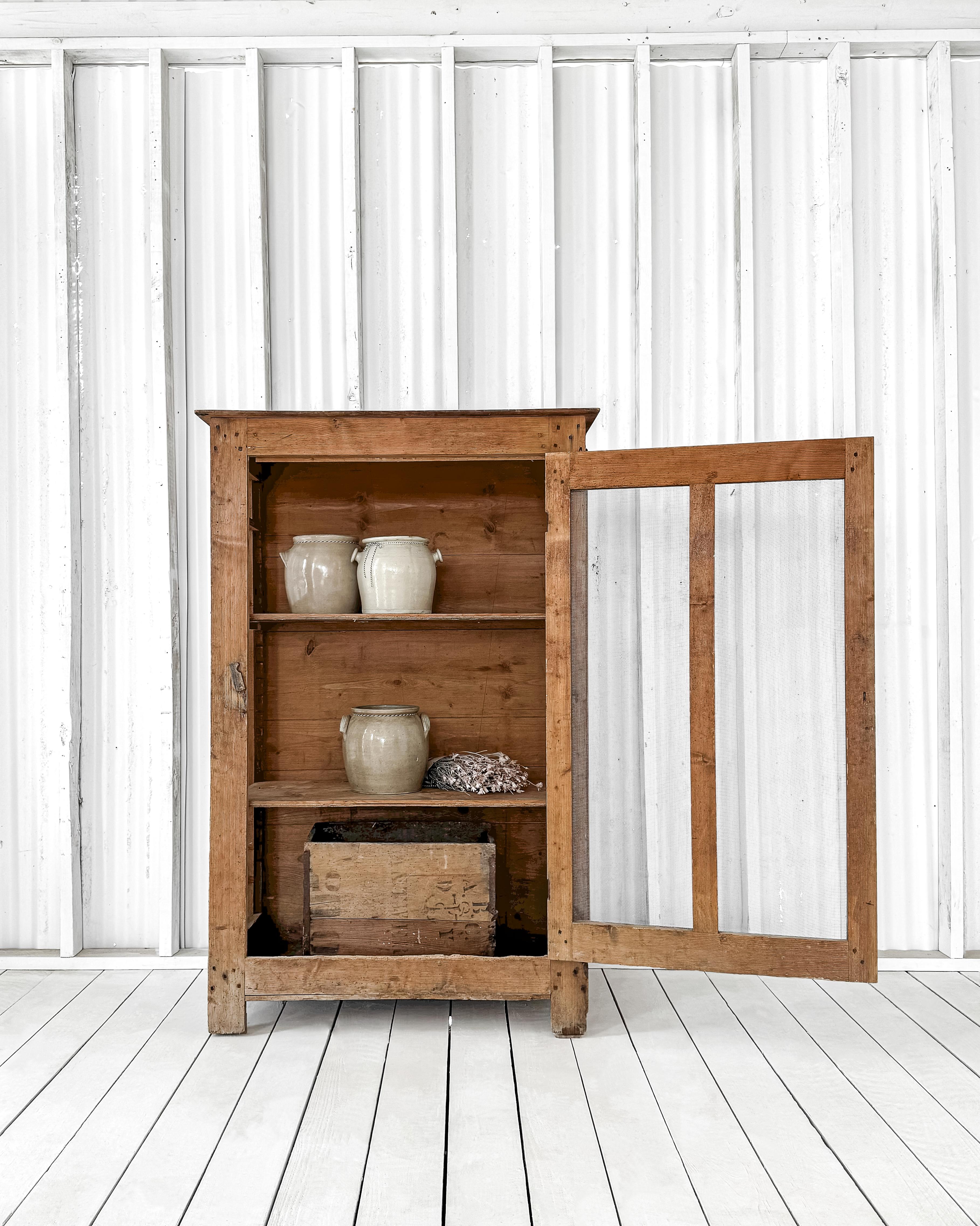 A charming primitive pine cupboard, crafted with a timeless design and exceptional durability. Constructed from solid pine using traditional pegged joinery techniques, this cupboard exudes strength and authenticity. The natural scrubbed finish