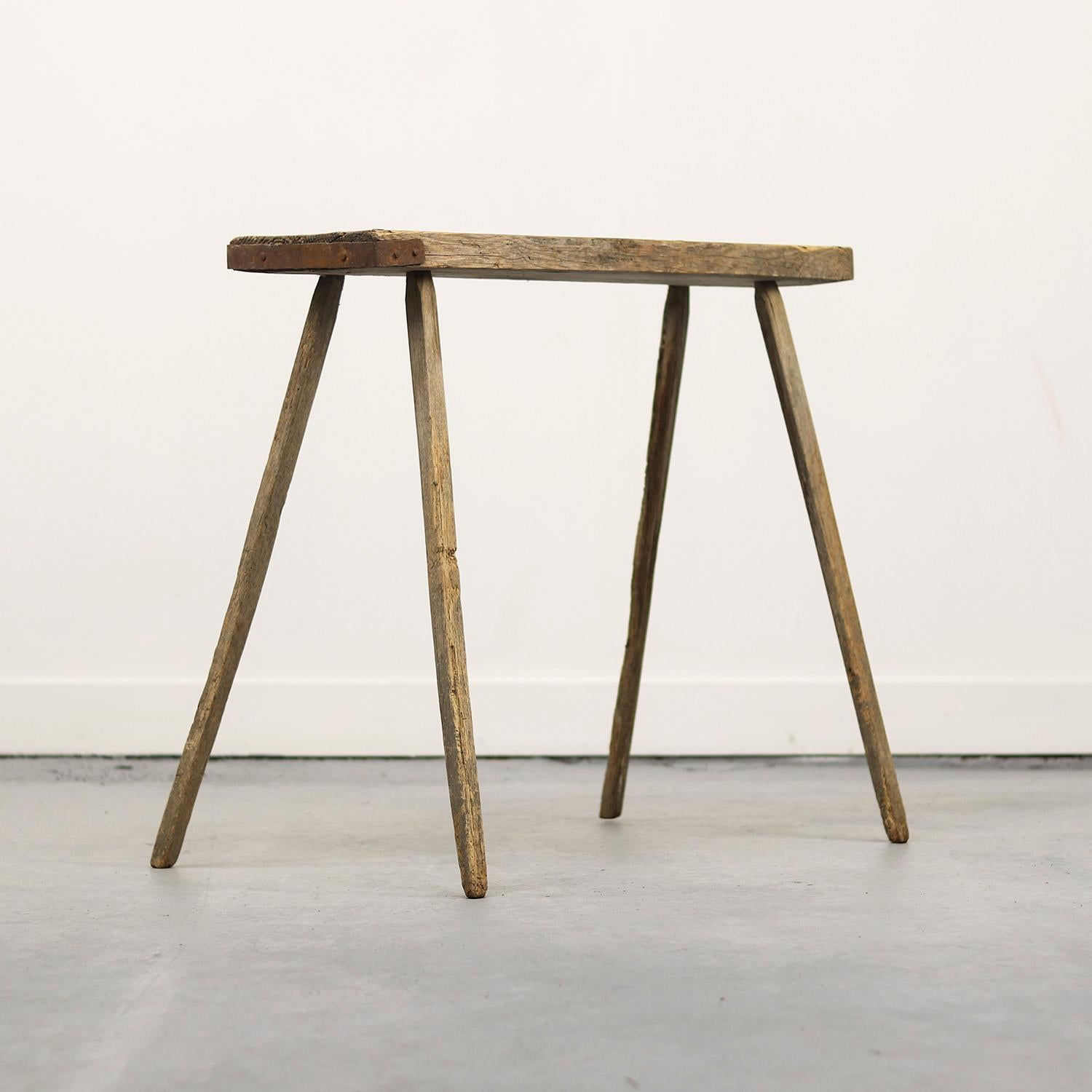 Cette table de travail en pin, haute et primitive, autrefois purement fonctionnelle en tant que meuble, s'est transformée en un objet élégant et distinctif. Construite avec des assemblages traditionnels à tenons et mortaises, la table est