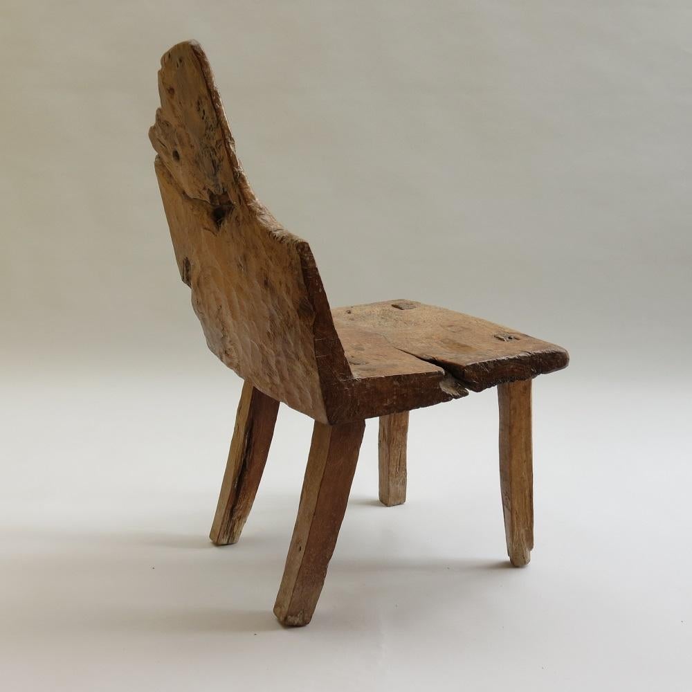 A rare antique primitive chair of unusual design from the 1820s.  The seat and back are made from one piece of Walnut timber.  The legs are tenoned through the solid seat and wedged to hold.  Wonderful tool marks are visible all over the chair from