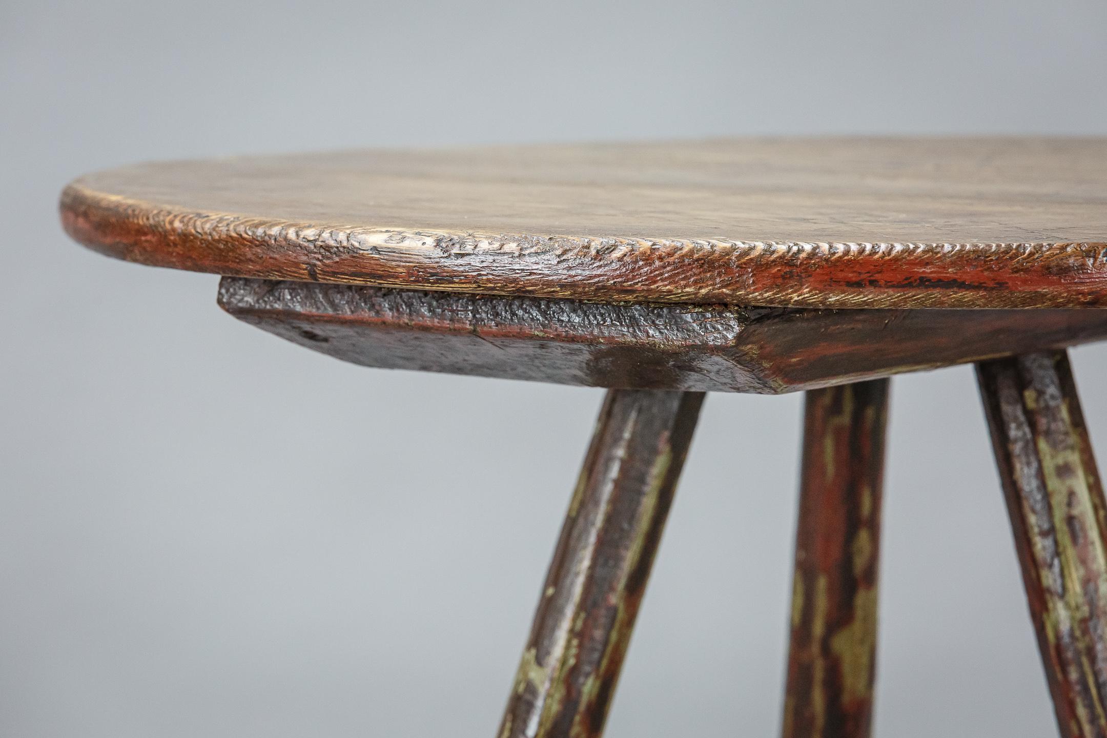 19th century primitive cricket table, remnant layers of historical paint to the base. various scratch decoration to the surface. Wales. Signs of wear and patination.