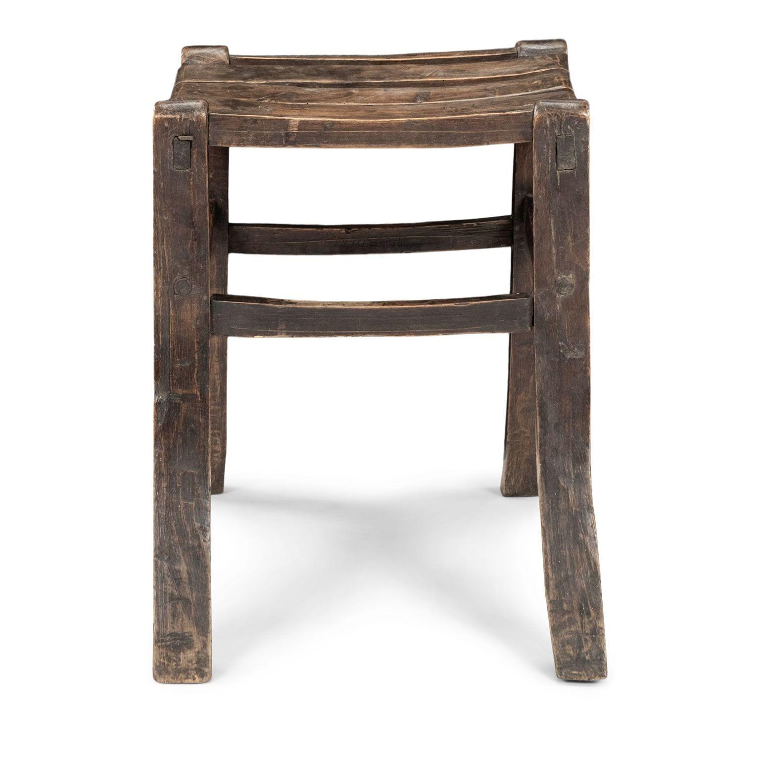 Primitive Welsh splayed leg stool with rectangular-shaped slatted seat. This charming dark brown color wooden stool was probably built and used on a farm. Contours of stool’s surface is irregular due to the crude tools used by its maker in the