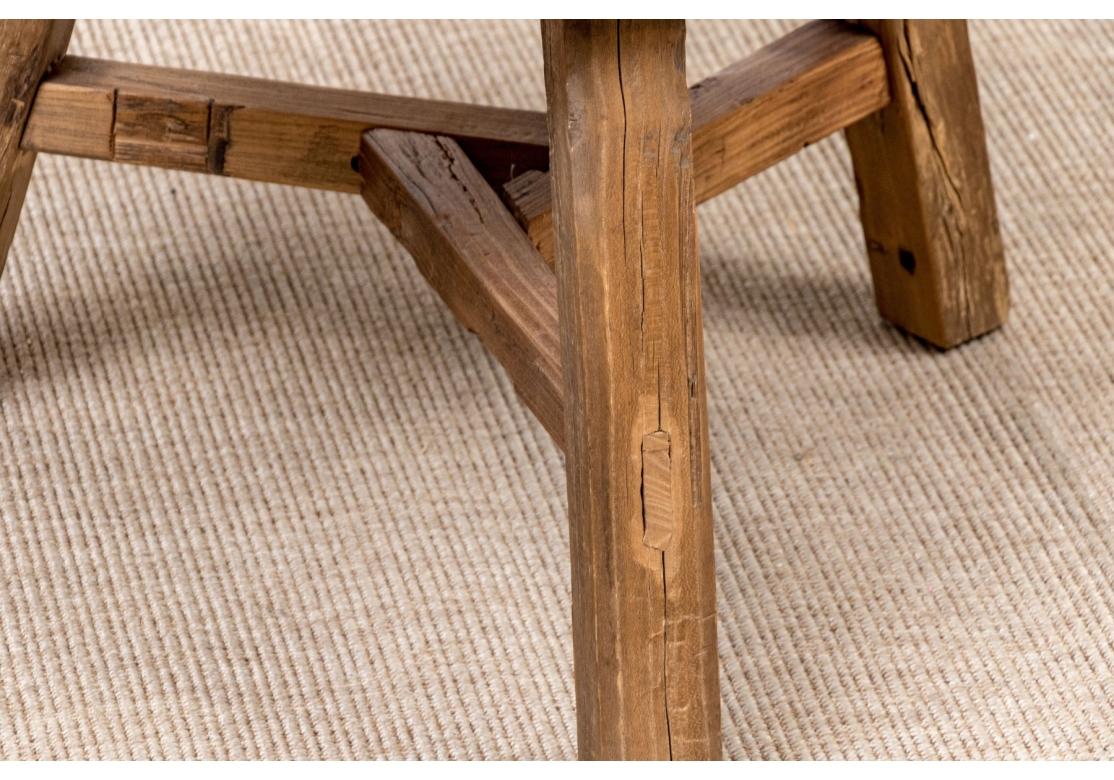 Table rustique avec un épais plateau en bois antique supporté par trois pieds avec des chevilles et un brancard à motif géométrique. La table peut être utilisée dans un grand nombre d'applications intérieures et peut être utilisée comme table