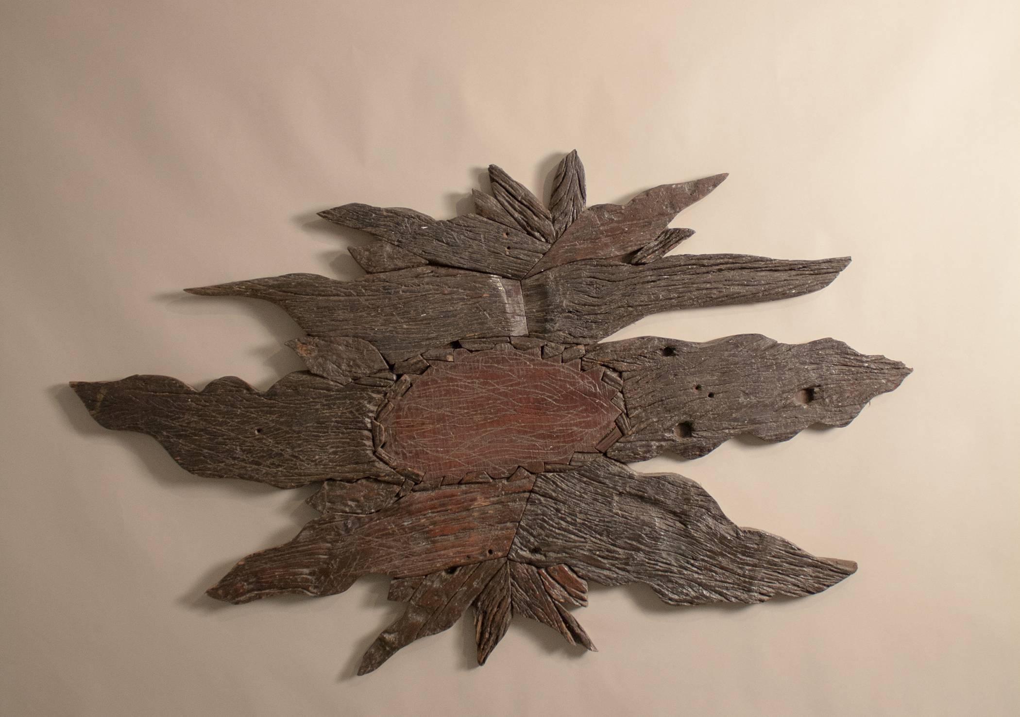 An organic Folk Art wall decoration crafted from attentively joined pieces of richly textured reclaimed hardwood. We see a nearly five feet by three feet sun or flower, but the panel is abstract enough to be open to interpretation and hung