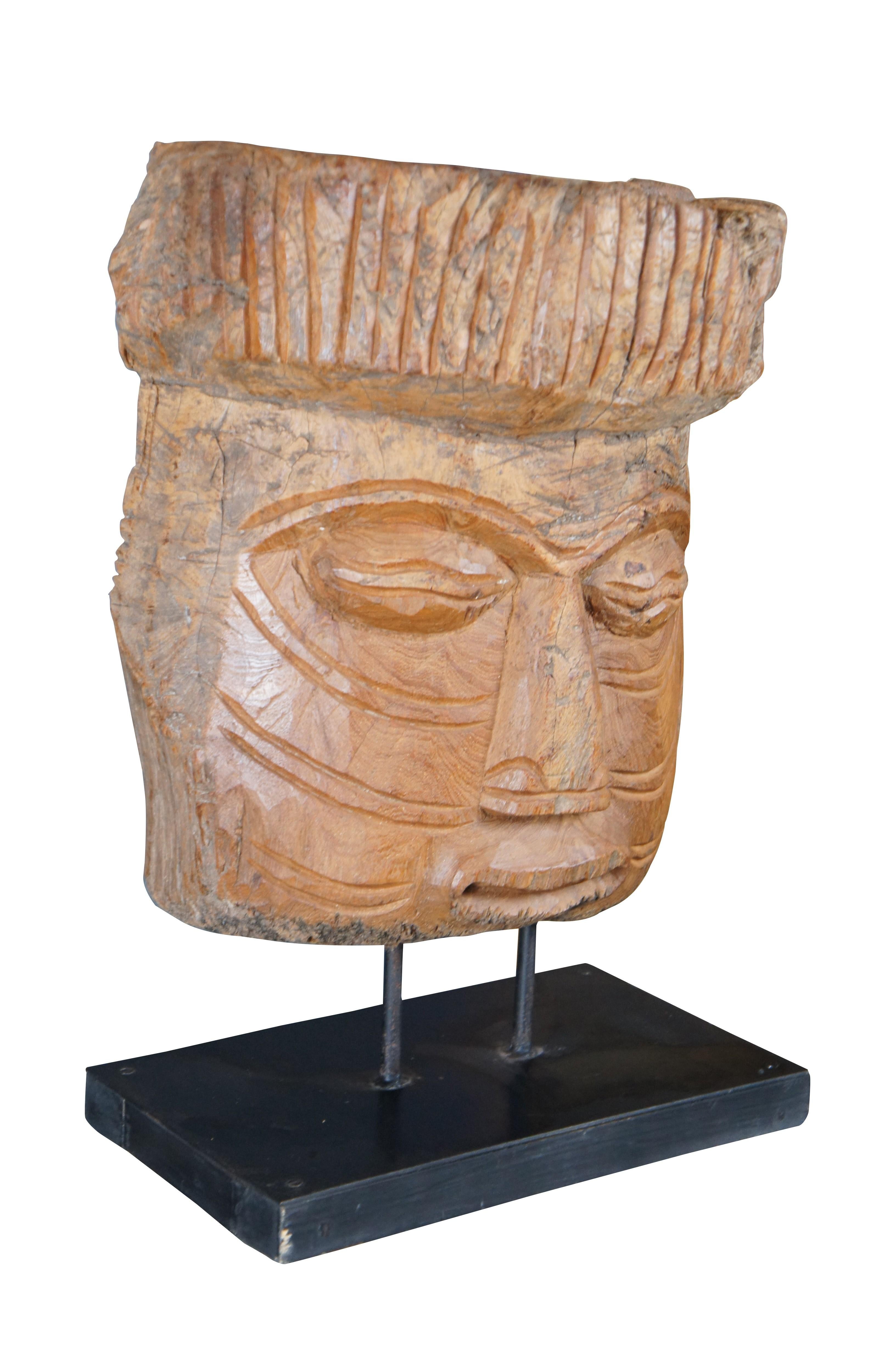 Late 20th Century Mesoamerican style tribal mask on black finished wooden stand. The mask is carved from part of a tree trunk with intricate detail.

Dimensions:
9.5