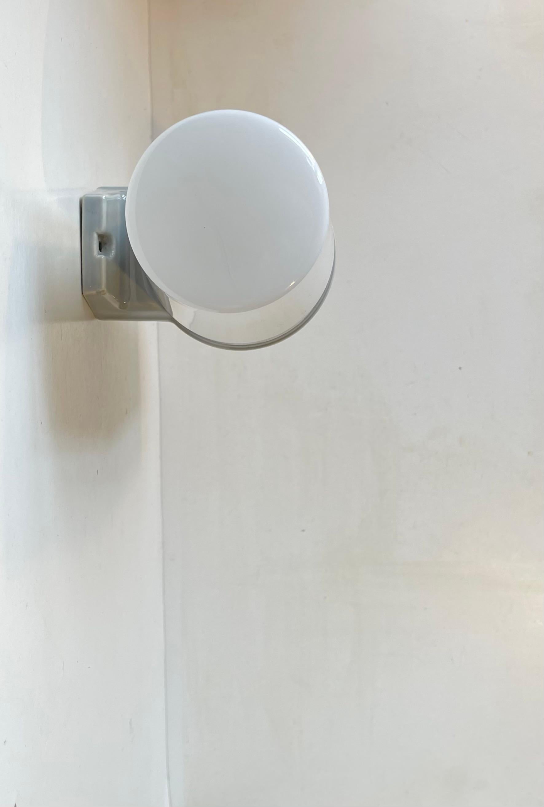Grande applique murale double convenant à l'éclairage de la salle de bain ou de l'extérieur. Conçue par le prince Sigvard Bernadotte pour la société suédoise Ifö dans les années 1960. Monture en porcelaine émaillée grise avec 2 abat-jours en verre