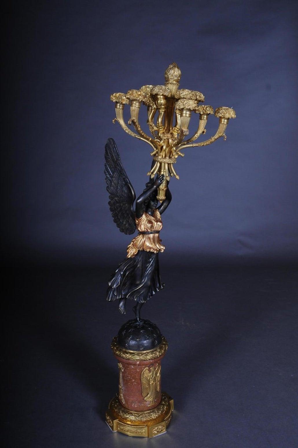Bronzo cesellato e fuso in modo estremamente fine. Figure completamente scolpite (Viktoria). Portando sulla testa e sostenendo con le mani l'albero a forma di torcia con 12 cornucopie, fari curvi. Questo modello è uno dei lampadari più
