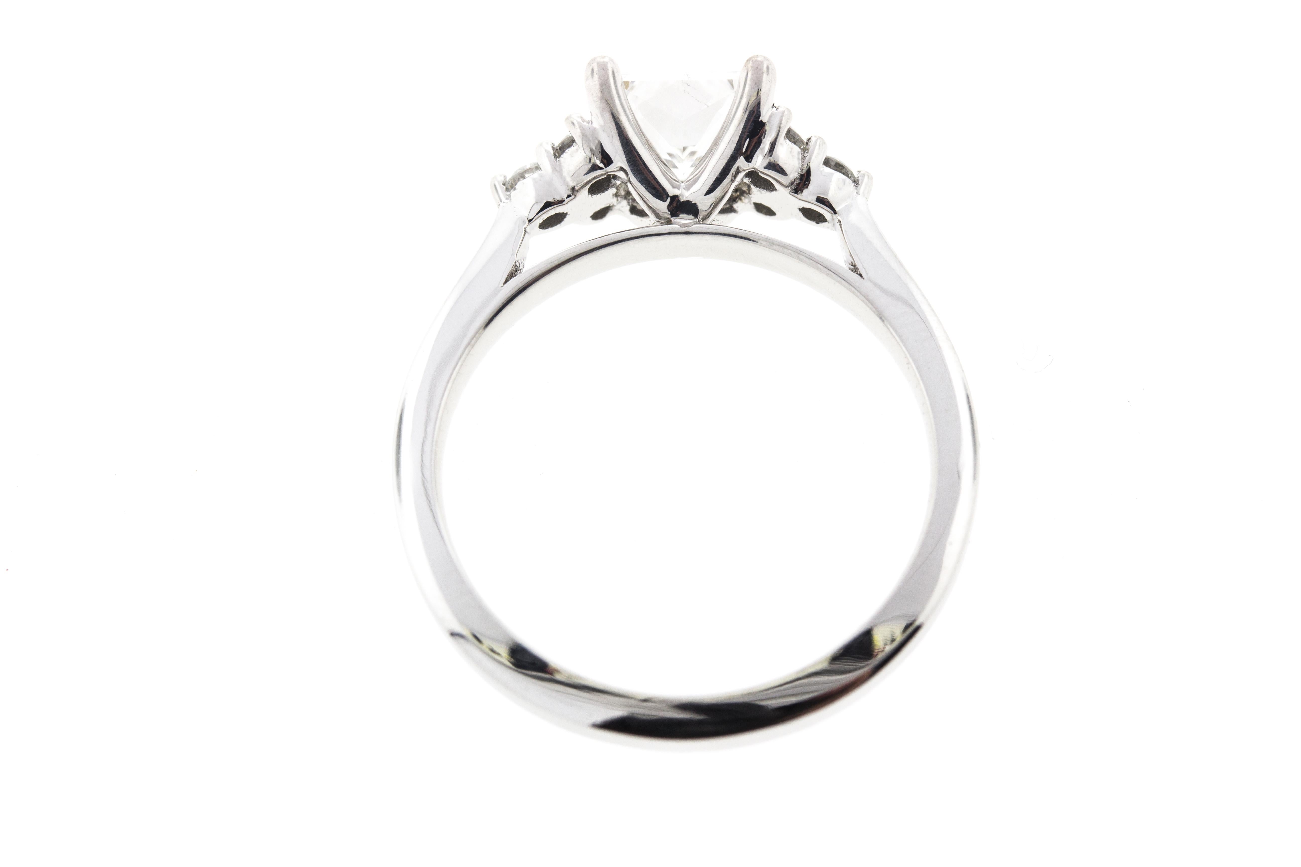 This ring is crafted in 14k white gold and contains an Princess Cut Diamond (1.07 total carat weight, E color, VS2 clarity,  surrounded by 6 Round Brilliant Cut Diamonds (0.24 total carat weight, F color, VS clarity).

Please note that each piece we