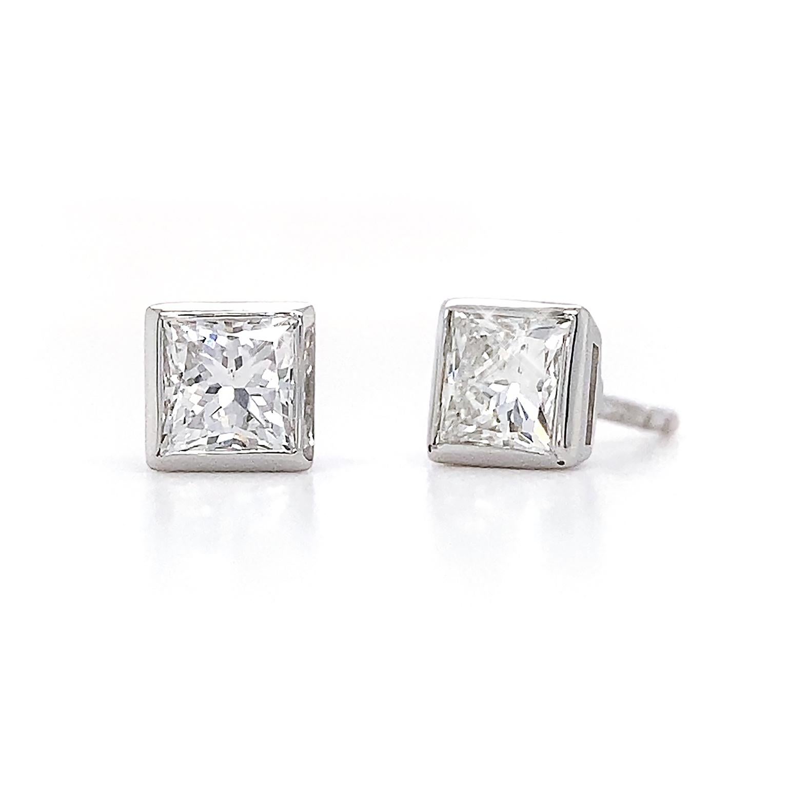 These stud earrings embrace a monochrome aesthetic. The jewel of choice is a princess cut diamond, combining brilliance with geometric lines. Each gem is bezel set in 14 white gold, protecting the diamonds. The precious metal’s icy hues coordinate