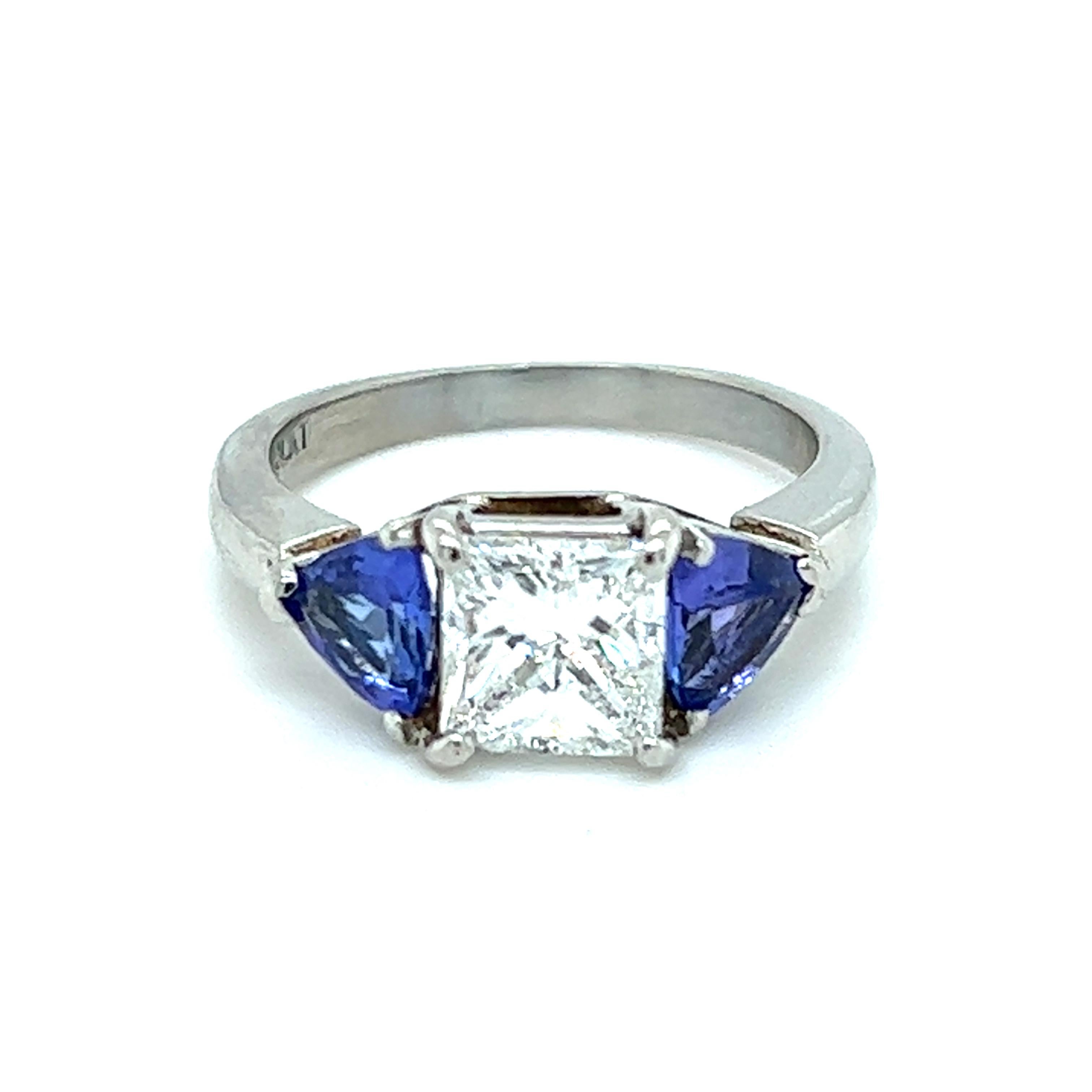 One platinum engagement ring set with one (1) 1.16 carat princess cut diamond with E color and VS2 clarity. The center stone is  flanked by two (2) trillion cut tanzanite stones measuring 5.5mm. The ring is stamped PLAT and is a finger size 6.5. The