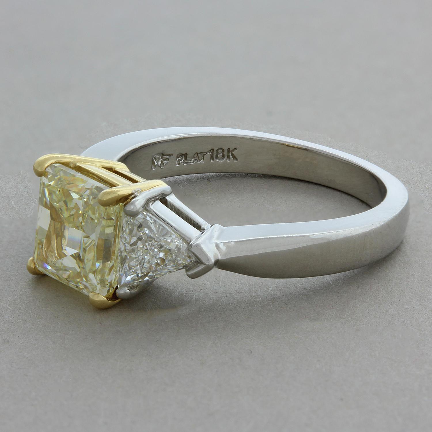 This contemporary engagement ring features a 2.01 carat princess cut fancy yellow diamond in an 18K yellow gold setting. The center diamond is accented by two trillion cut diamonds weighting a total of 0.70 carats, set in platinum. A timeless and