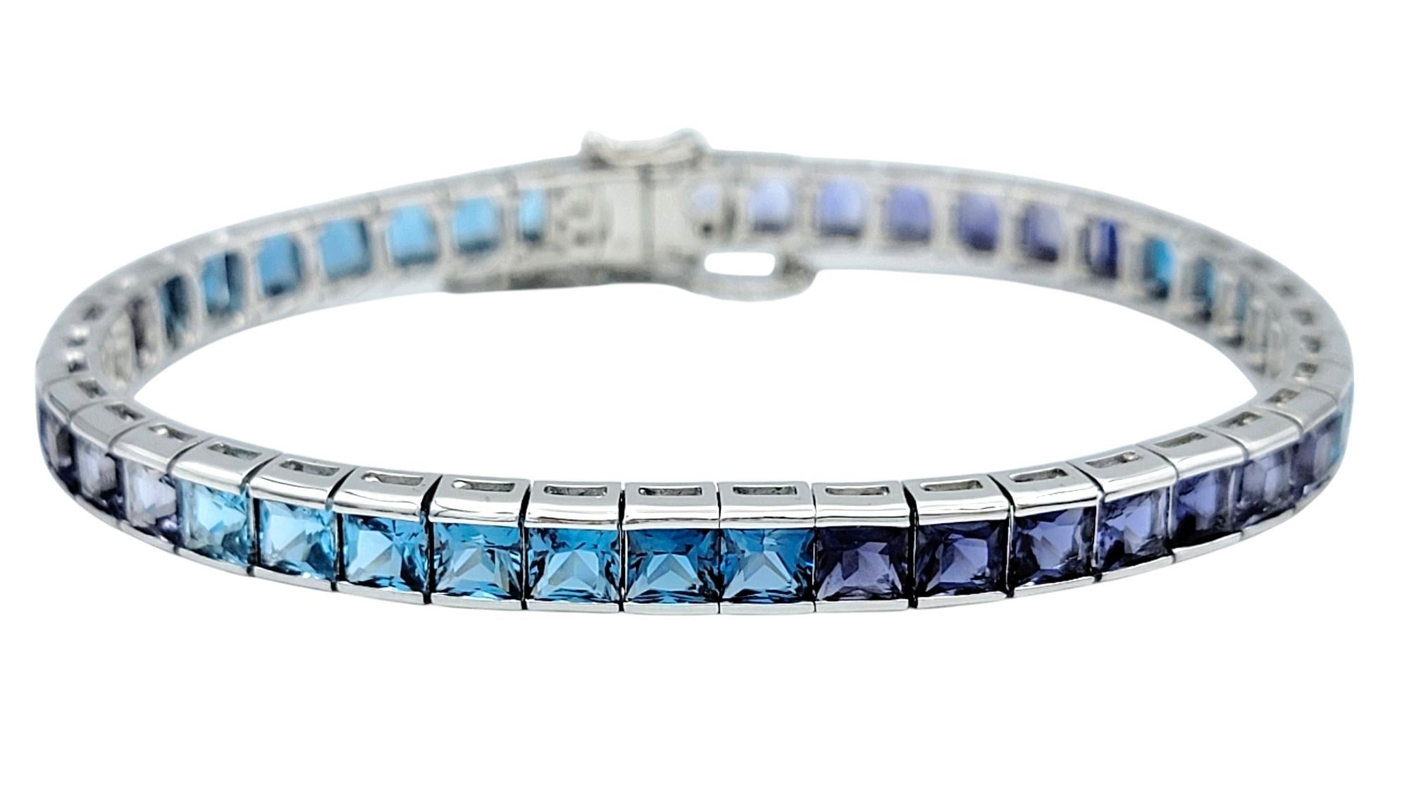 Indulge in the serene beauty of this exquisite tennis bracelet, a harmonious blend of sophistication and vibrant color. Set in luminous 18 karat white gold, this piece features a captivating gradient design with princess-cut iolites and blue topaz