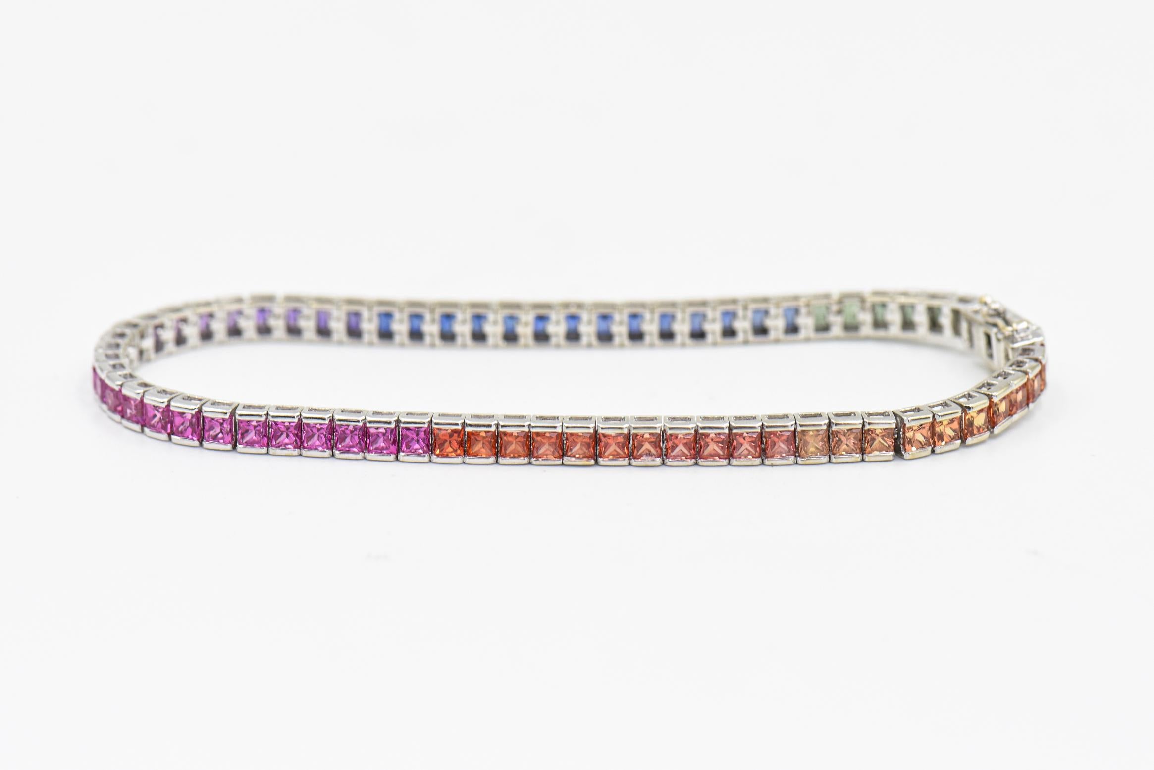 This colorful bracelet contains 69 multi color princess cut sapphires with an estimated total weight of 6.90 carats.  The colors from a light orange to a darker orange, pink to purple, and blue to green.  They are channel set in a 14K white gold