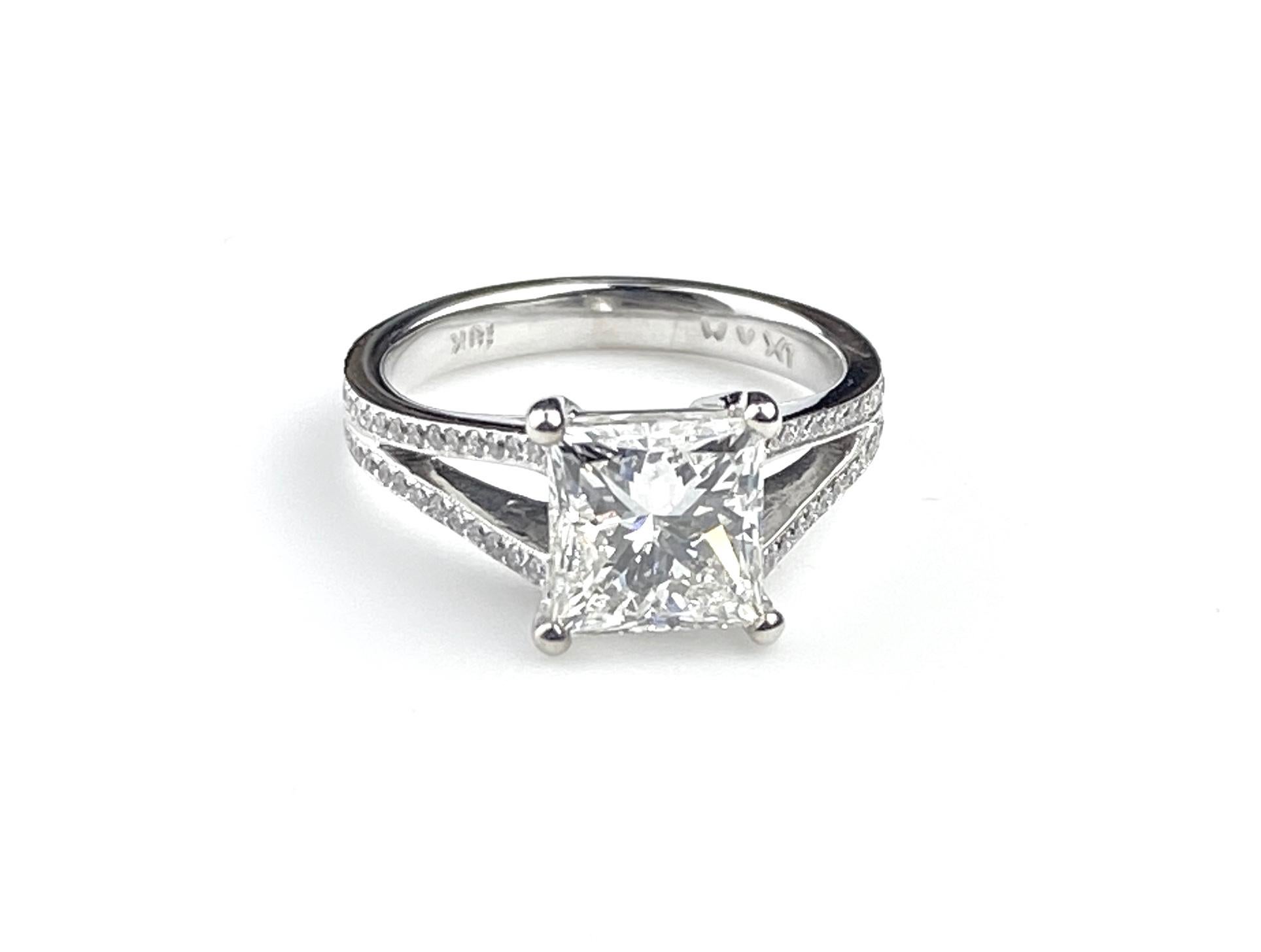 Split shank solitaire engagement ring set with 2.21ct Princess Cut center diamond, H VS1 GIA #2127143292. Setting in 18kt white gold with round cut side diamonds totaling 0.22ct. Side diamonds are F/G colour and VS/SI1 clarity. Current ring size 5.