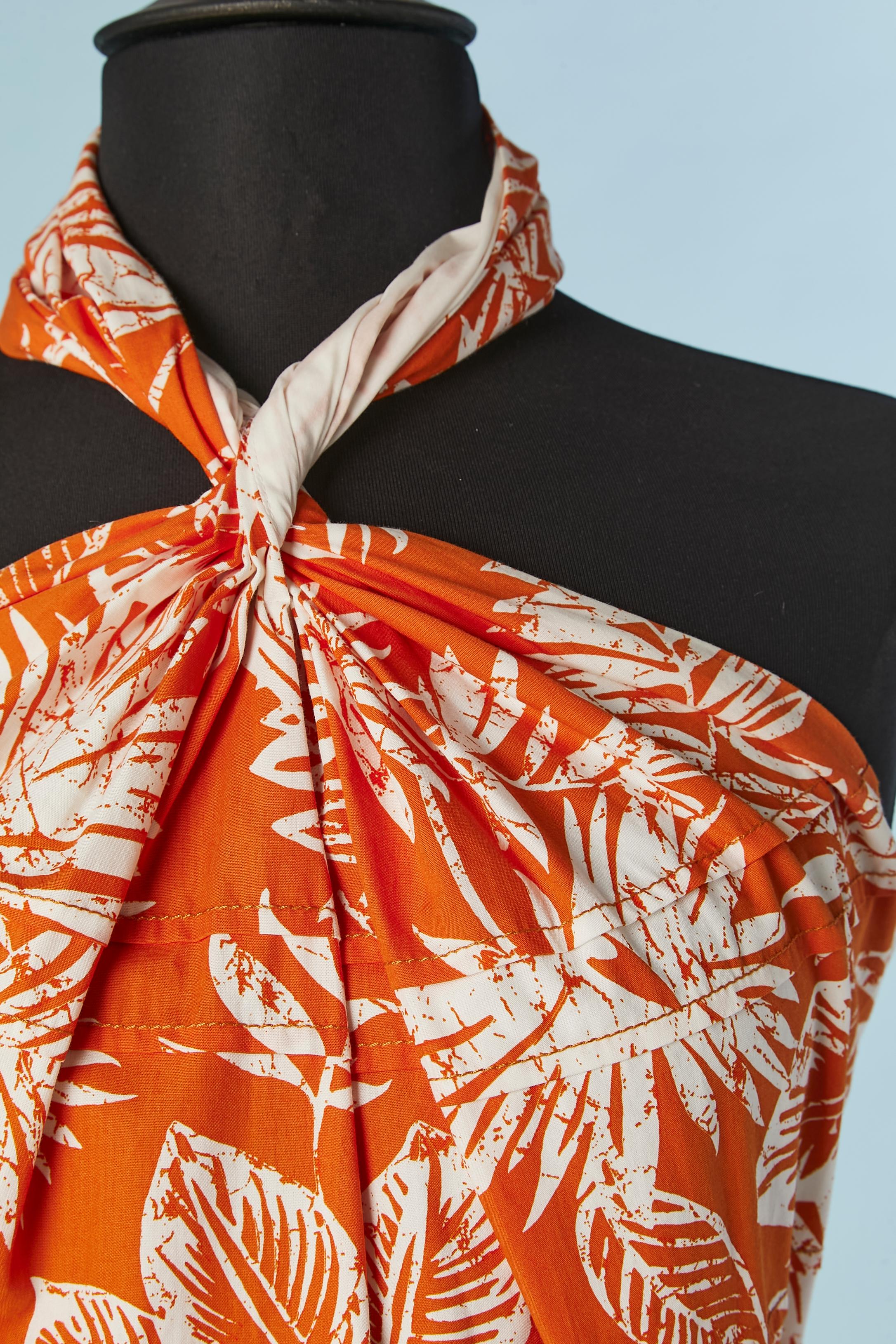 Robe imprimée en coton dos nu avec volants et encolure torsadée. 
Doublure : 75% coton, 17% polyamide, 8% stretch. 
Fermeture zippée au milieu du dos + tirette zippée et crochet de marque. Boutons recouverts de tissu et boutonnière derrière le cou.