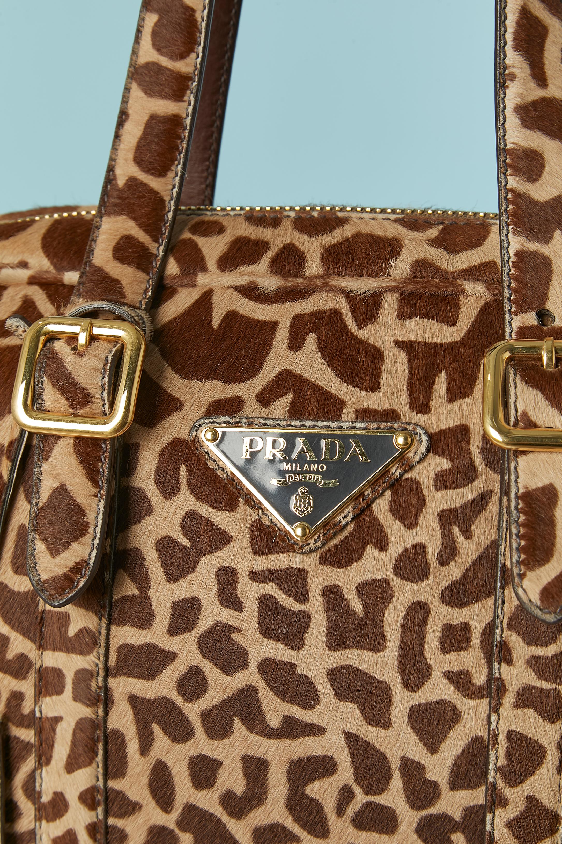 Borsa con manico superiore in pelliccia di vitello stampata. Fodera in nylon con marchio. Chiusura a zip sulla parte superiore. Una tasca con zip all'interno. Chiave e portachiavi ( la stringa del portachiavi è rotta. Scheda di autenticità e busta