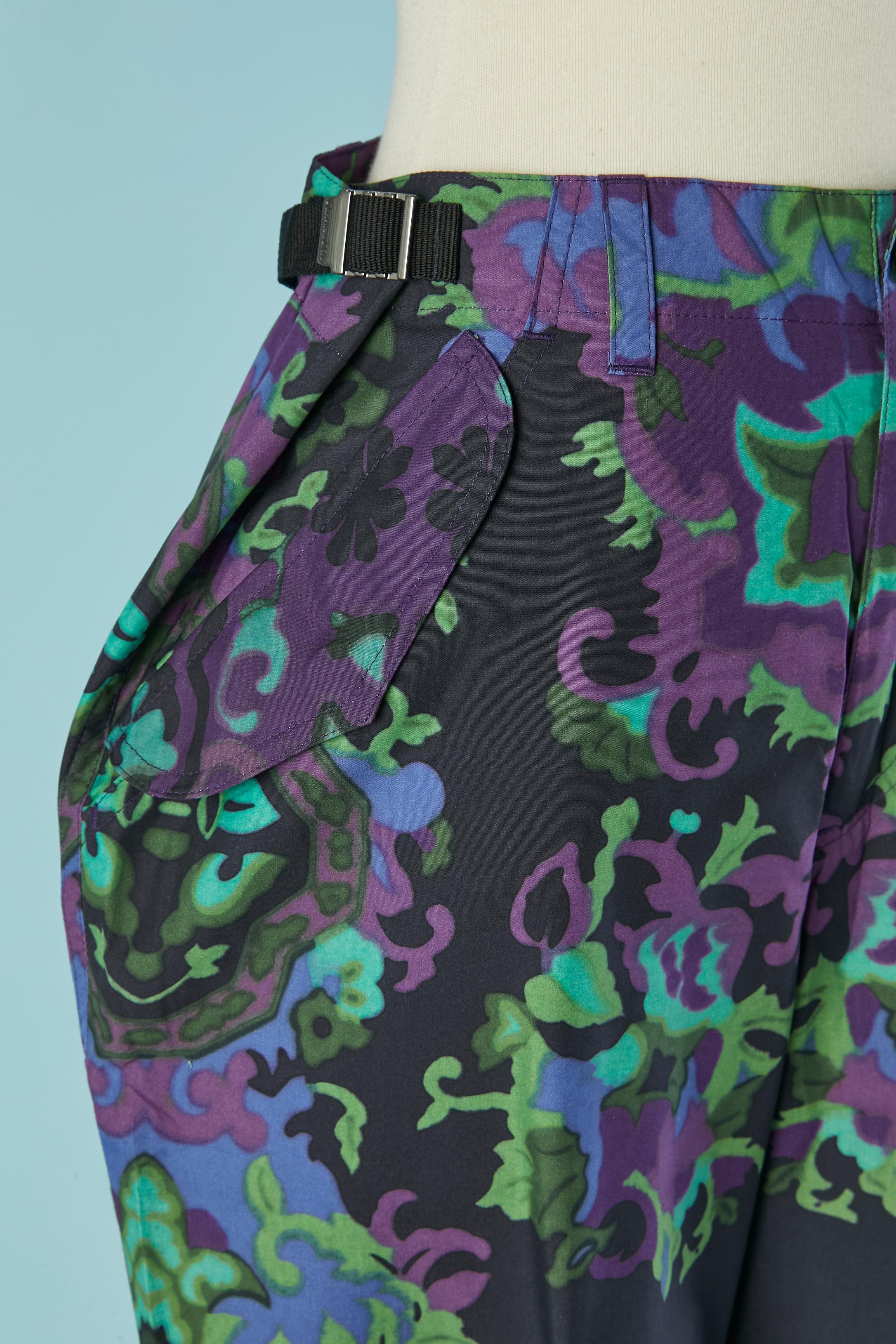 Pantalon en coton imprimé. Boucle de ceinture. Bouton et boutonnière marqués sur le milieu supérieur du devant. Sangle en nylon noir sur les deux côtés de la taille pour ajuster le tour de taille. 3 poches sur le devant et sur le côté avec rabat. 2