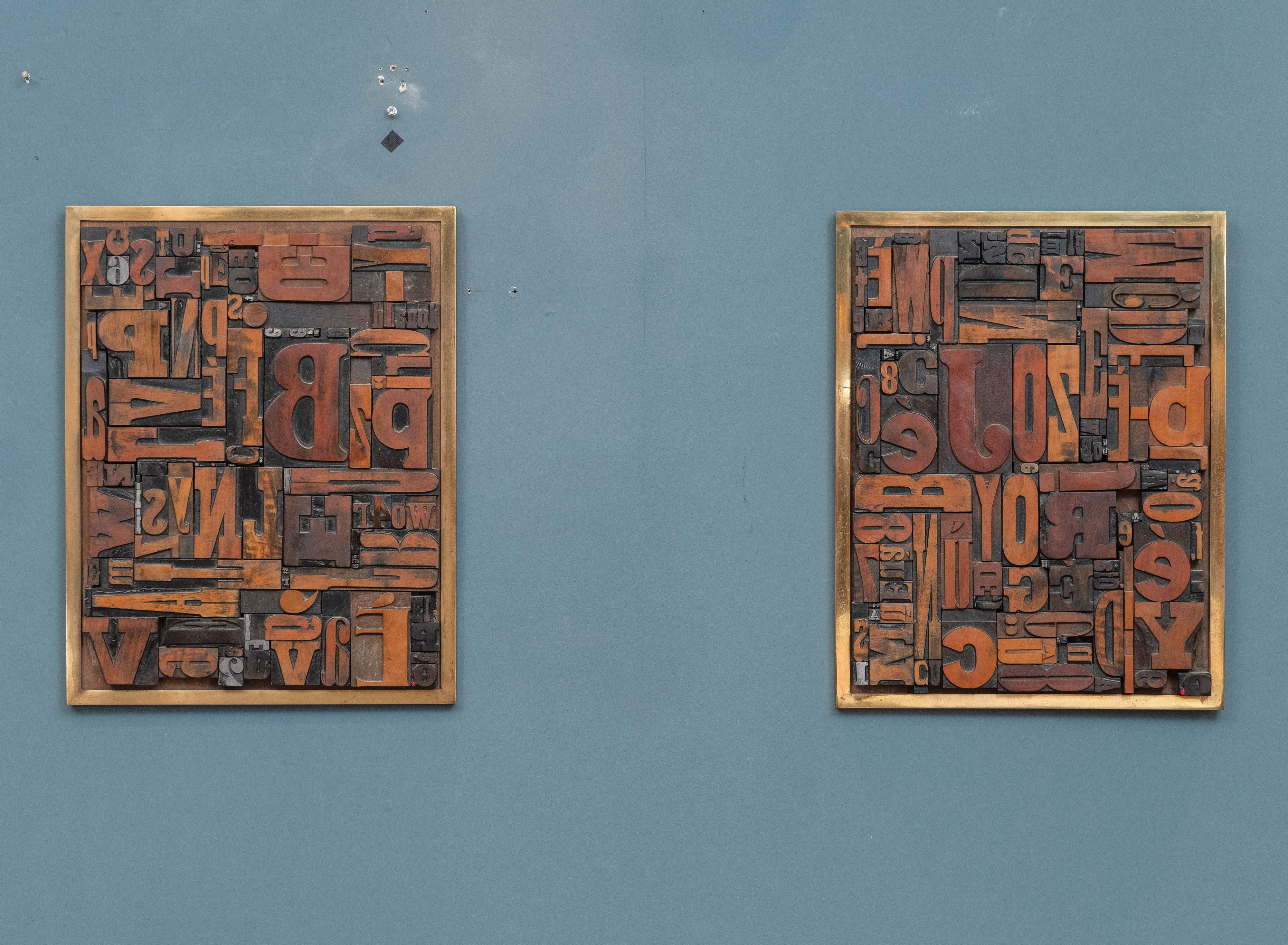 Folk Art printing press or letter block collage art. Interesting assortment of vintage printing blocks arranged in a whimsical visual pleasing manor in heavy brass frames. Matched pair of art works purchased from an estate in Connecticut. Signed and